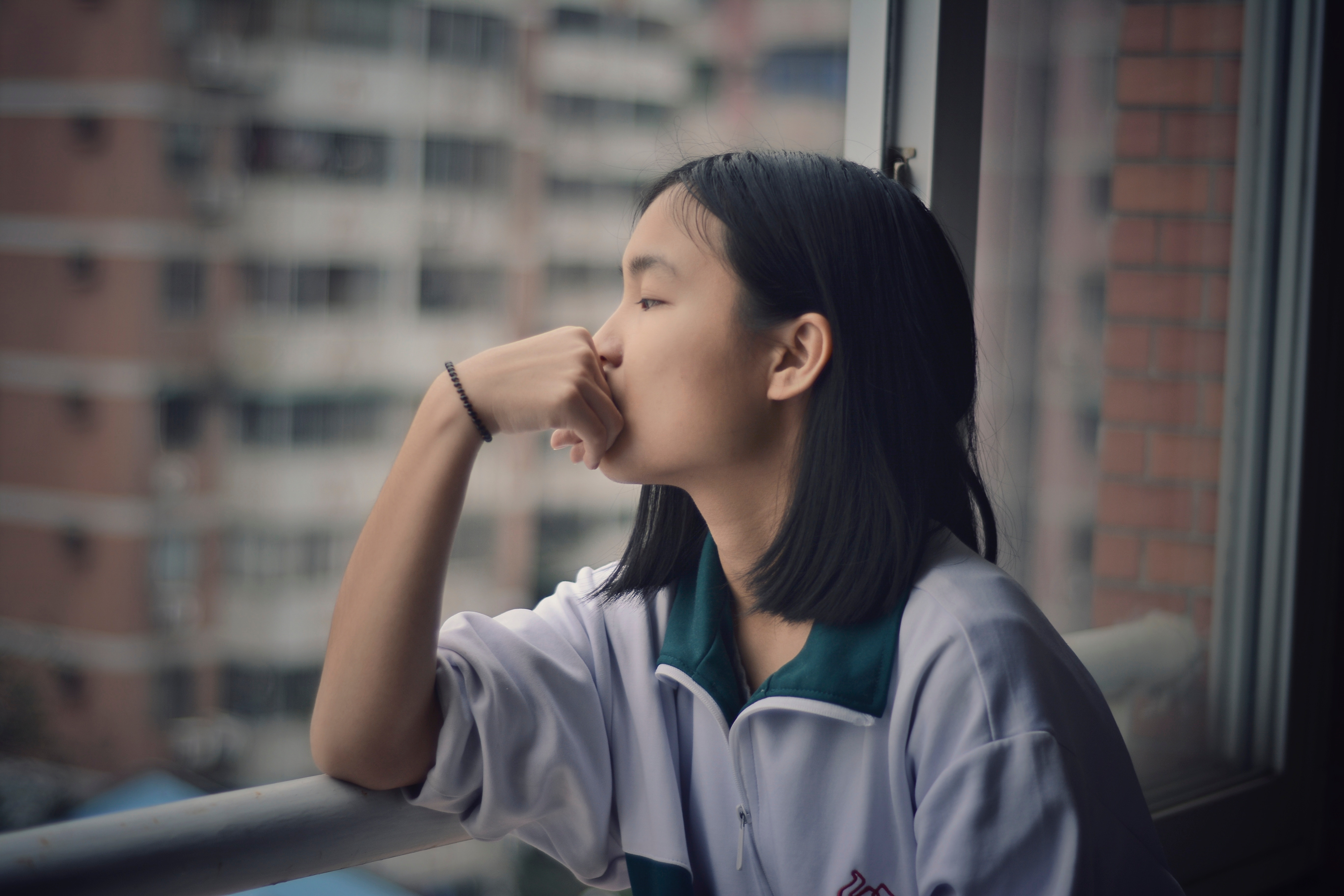 Girl looking out a window in a city HD Wallpaper