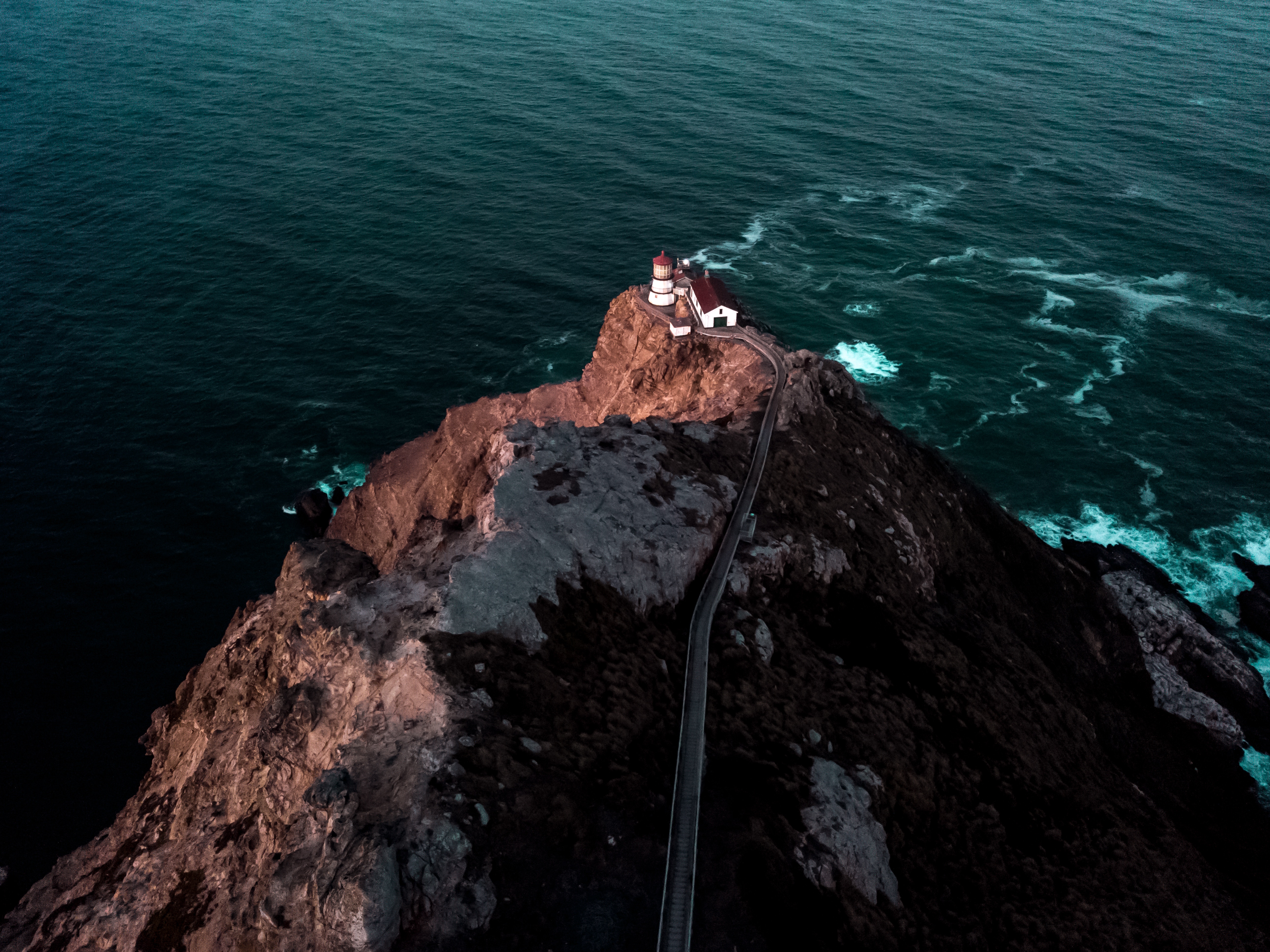 Lighthouse on a rocky cliff overlooking the ocean HD Wallpaper