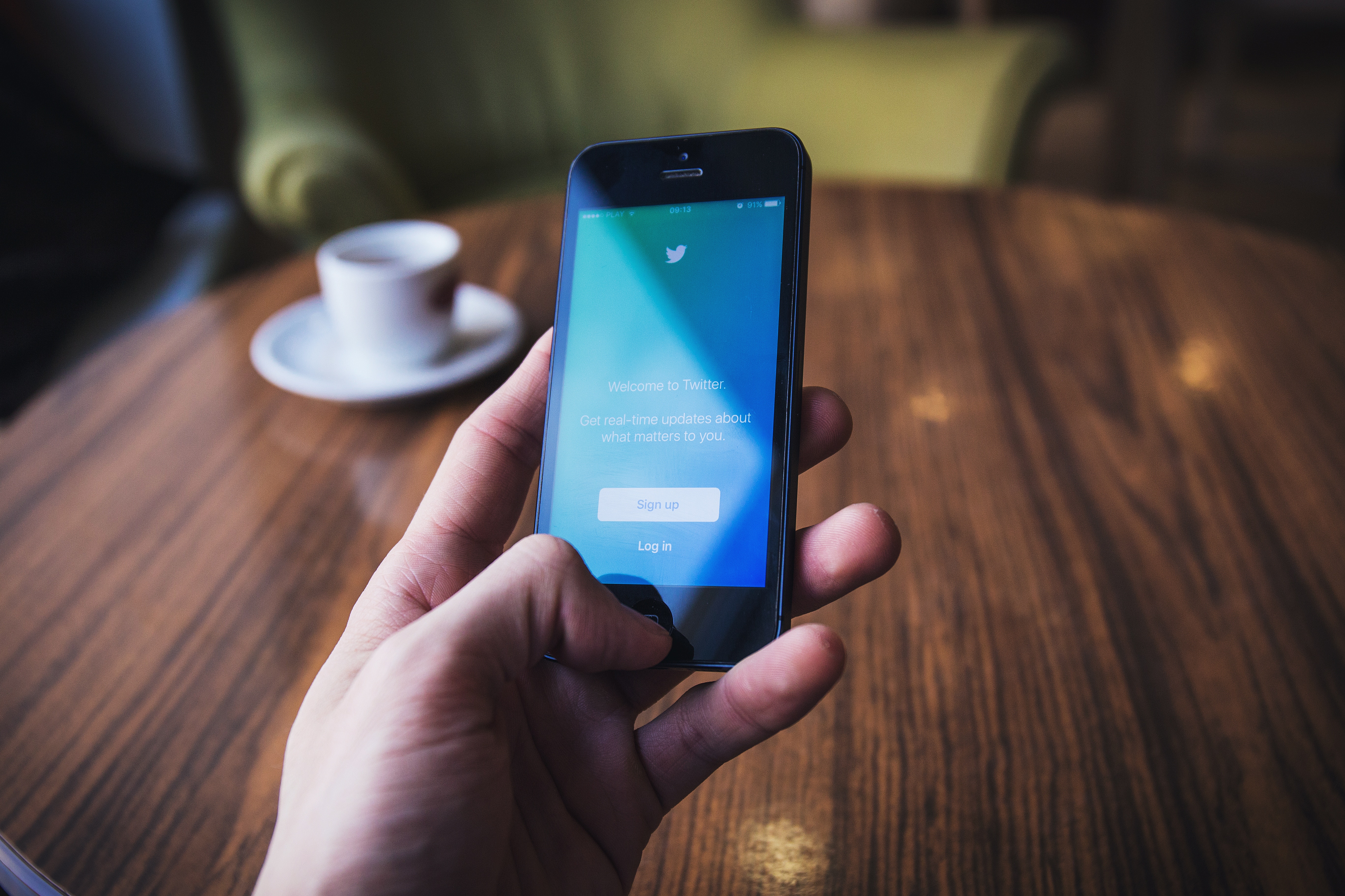 Hand holding iPhone with Twitter app open HD Wallpaper