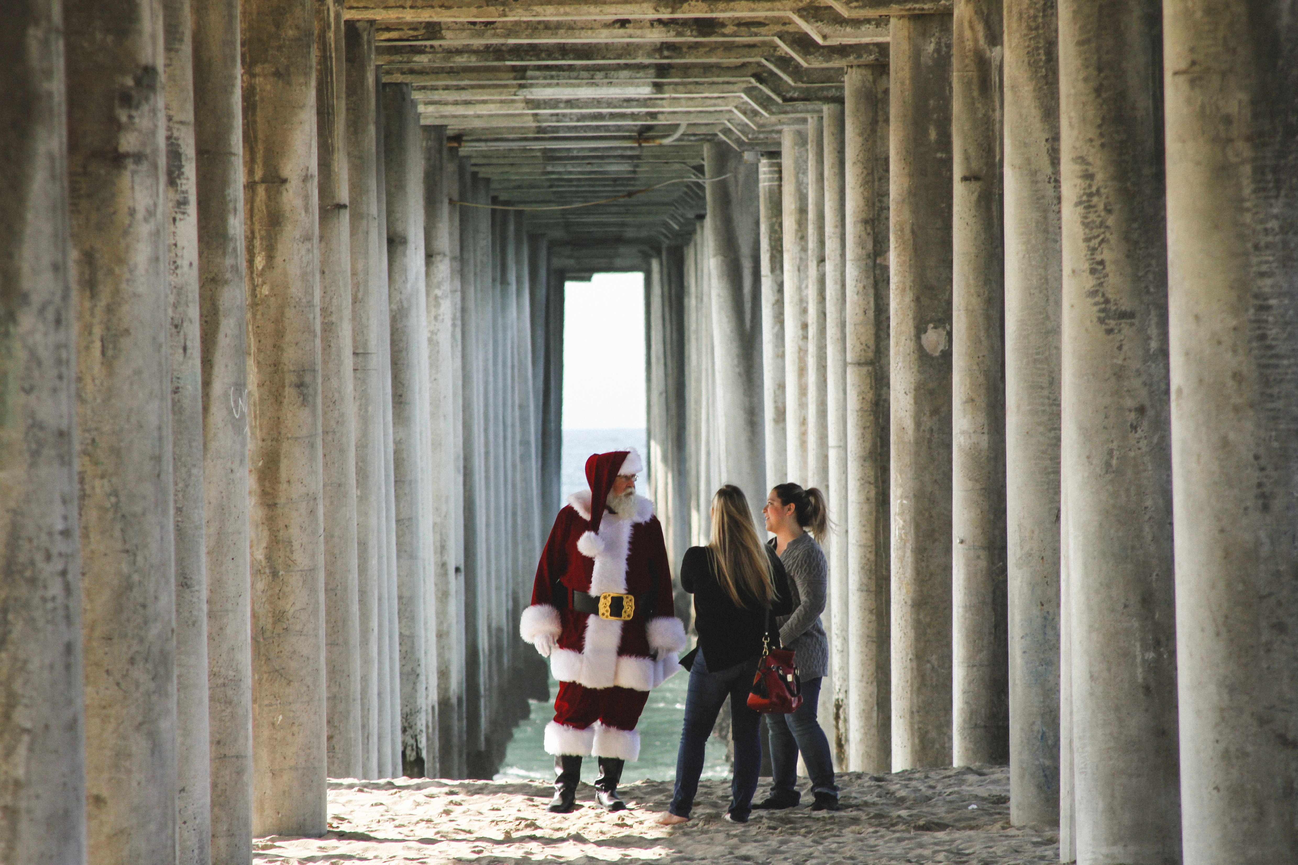 Santa Claus with two women under a pier HD Wallpaper