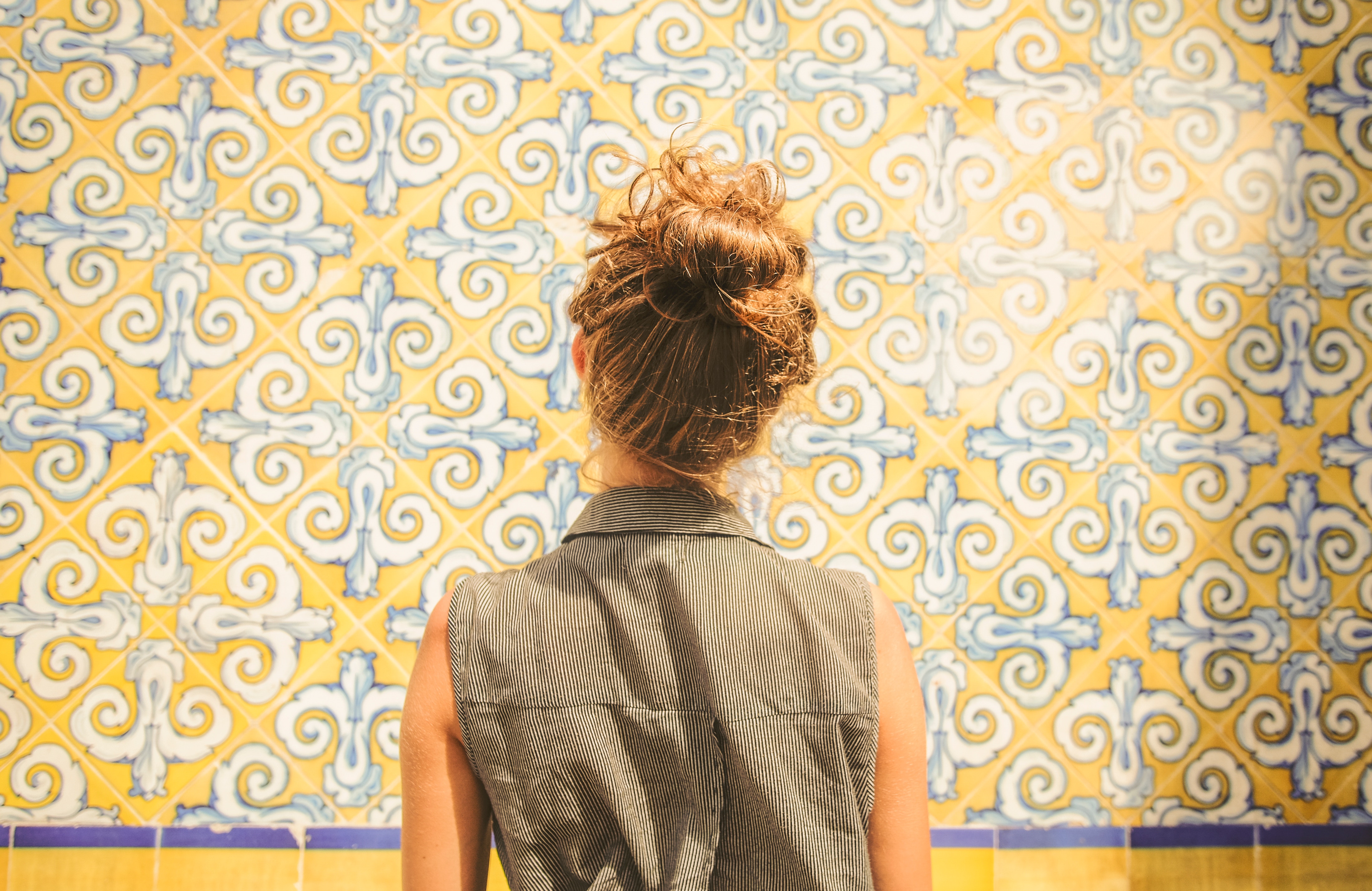 Woman with bun standing in front of yellow and blue tiles HD Wallpaper