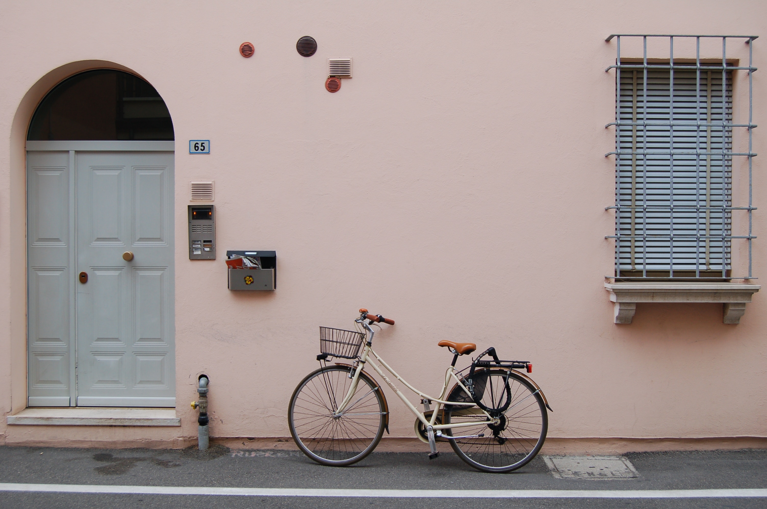 Bicycle parked by a pink wall with a door and window HD Wallpaper