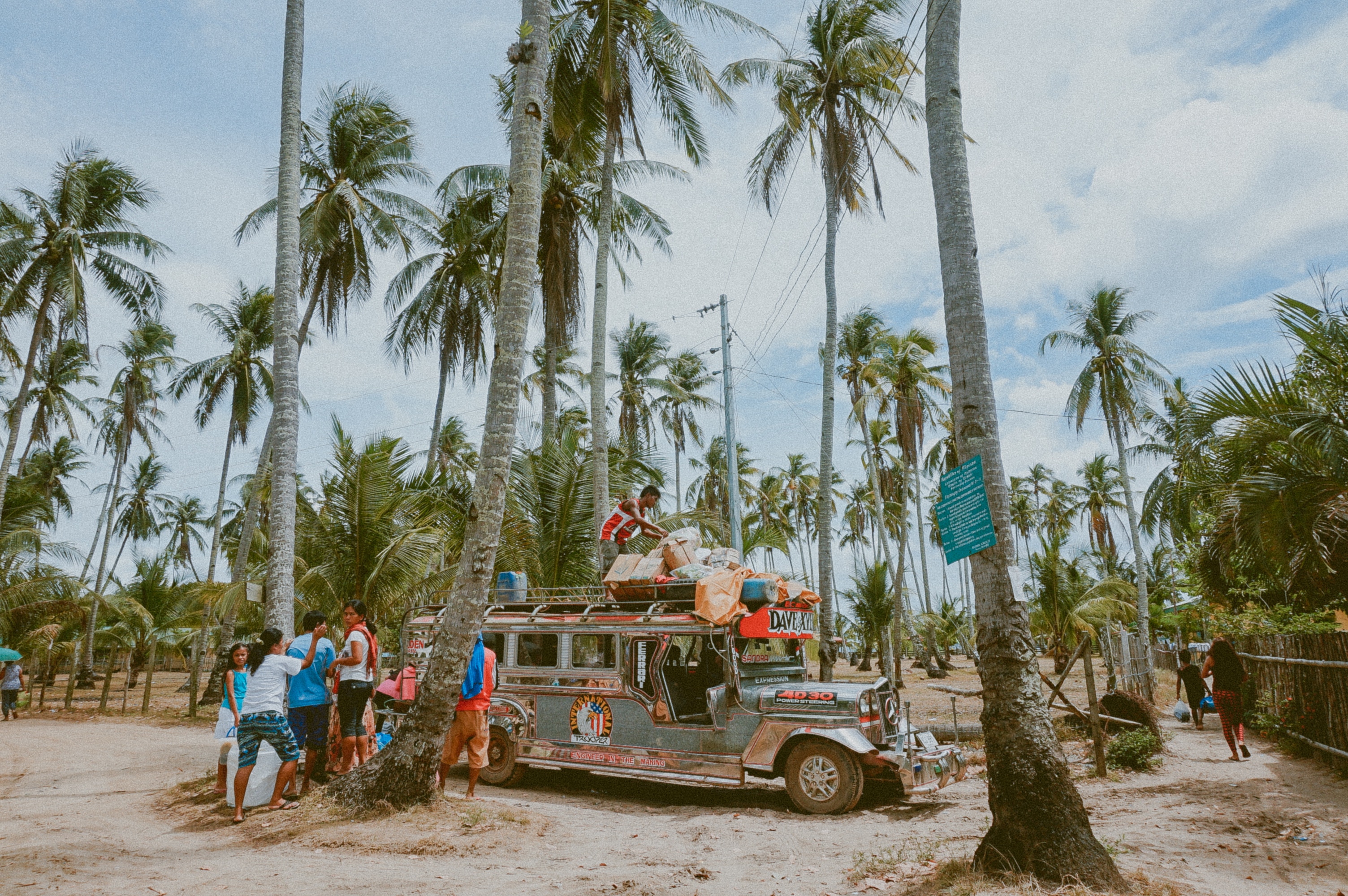 Jeepney loaded with goods under palm trees HD Wallpaper