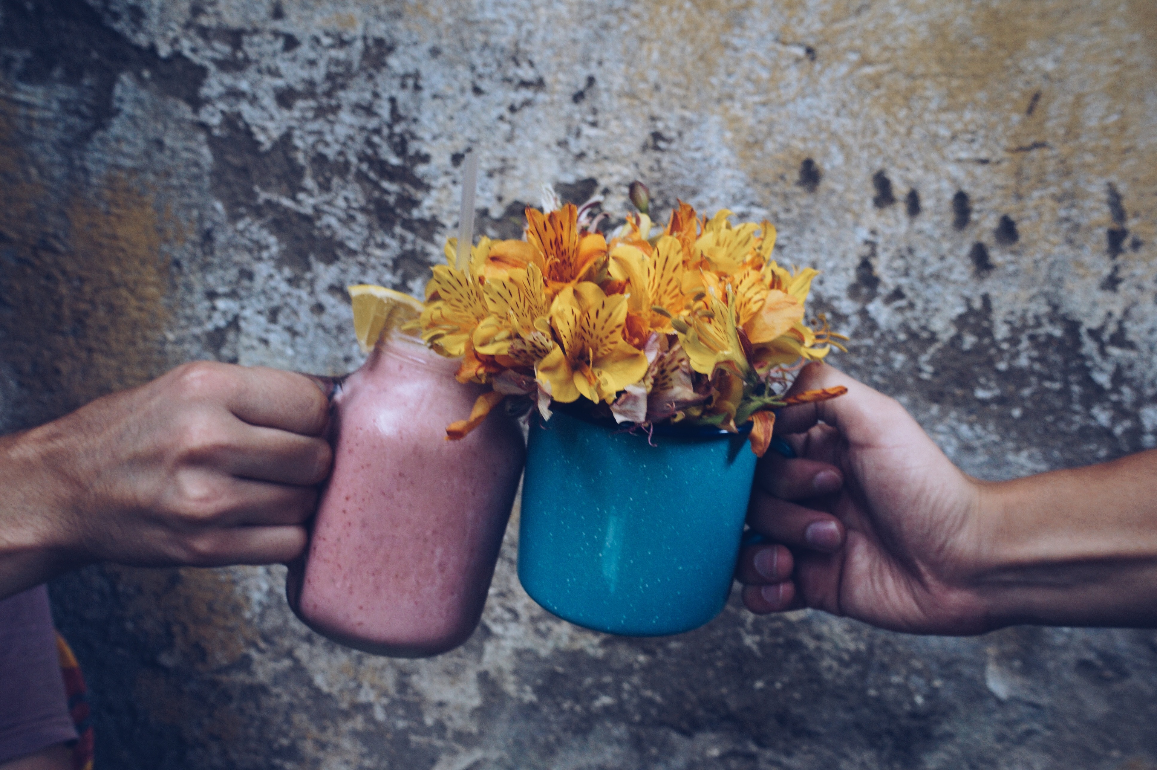Two hands holding a pink smoothie and a blue mug with flowers HD Wallpaper