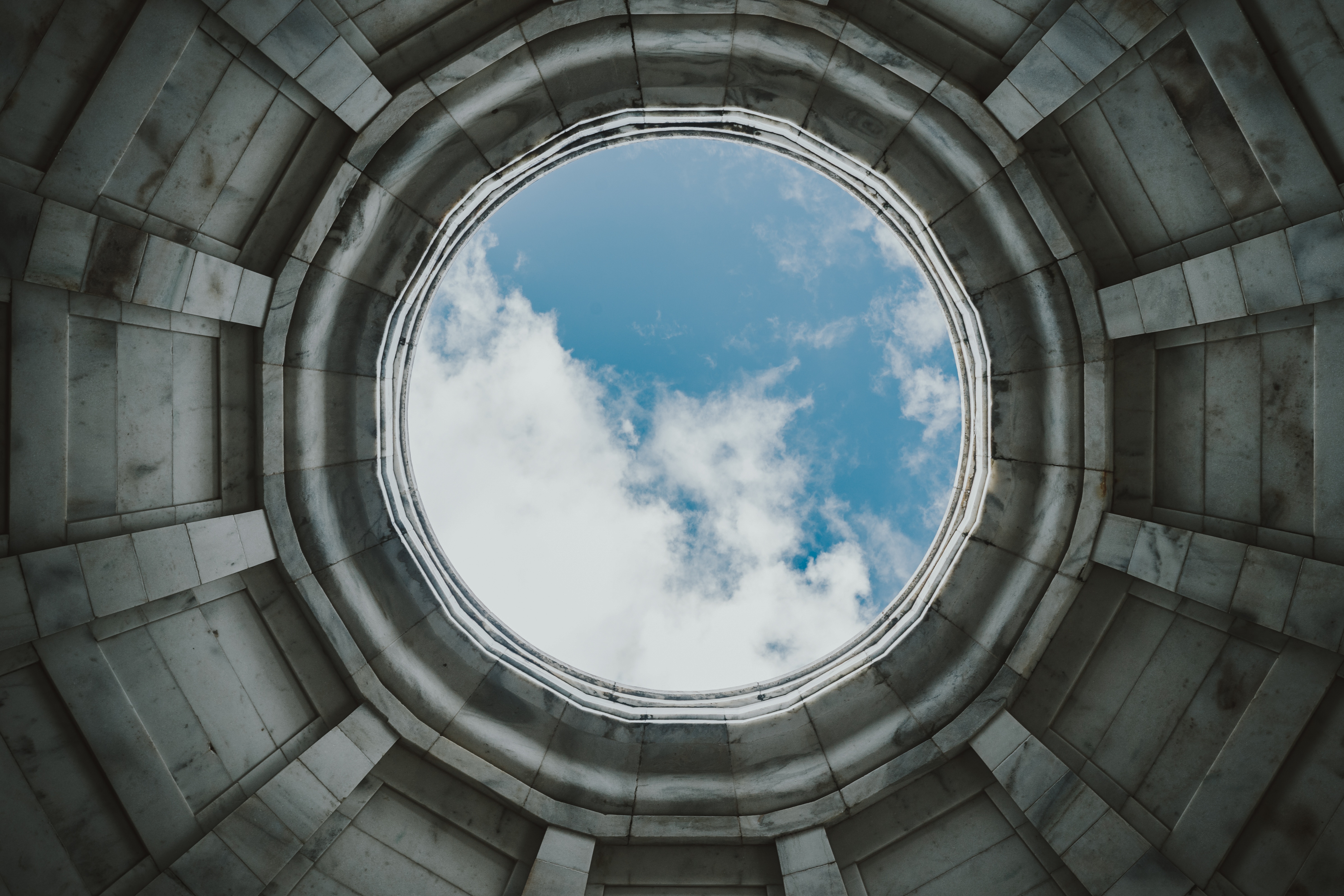 Looking up through a circular opening at the sky HD Wallpaper