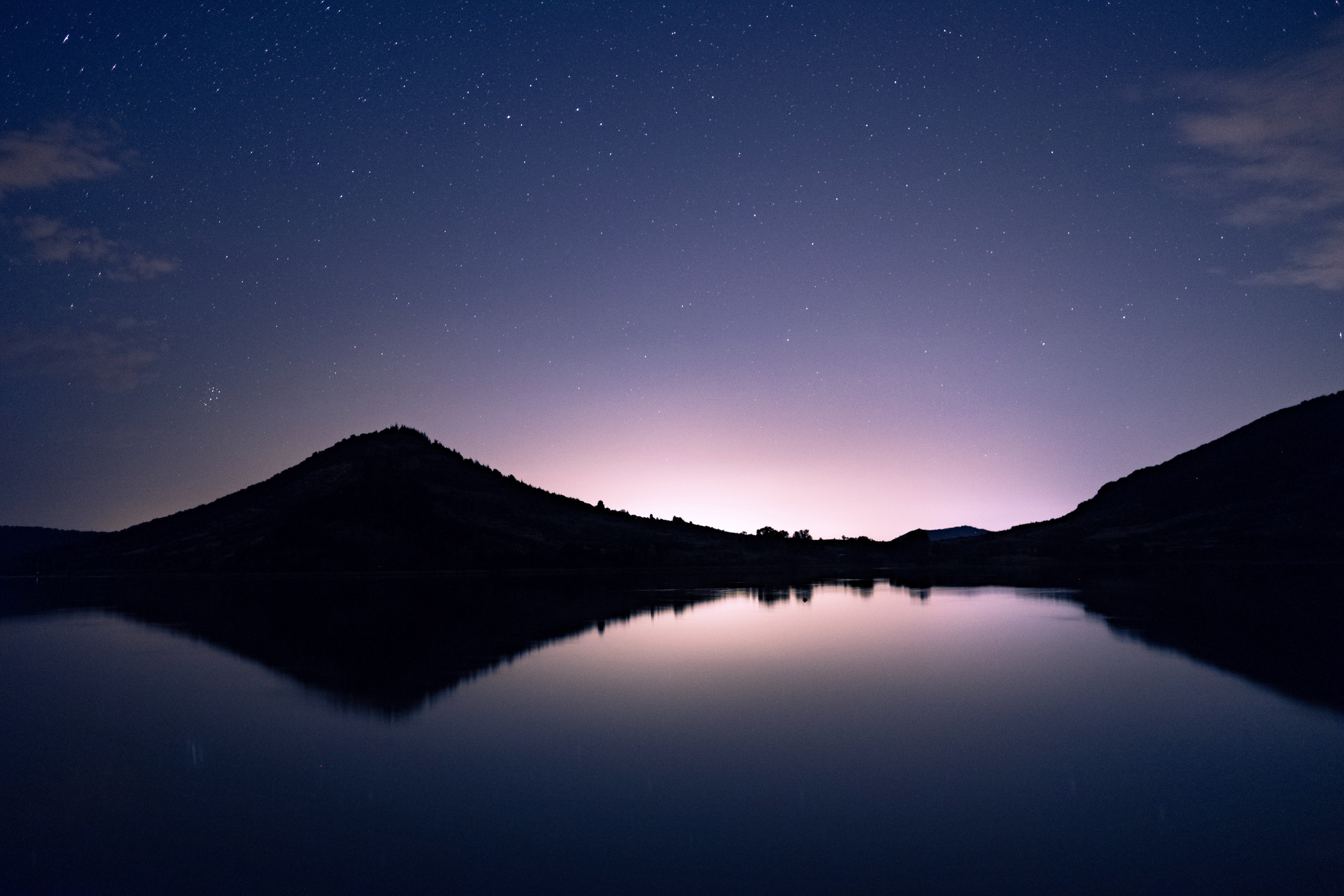 Silhouette of mountains reflected in a lake under a starry night sky HD Wallpaper