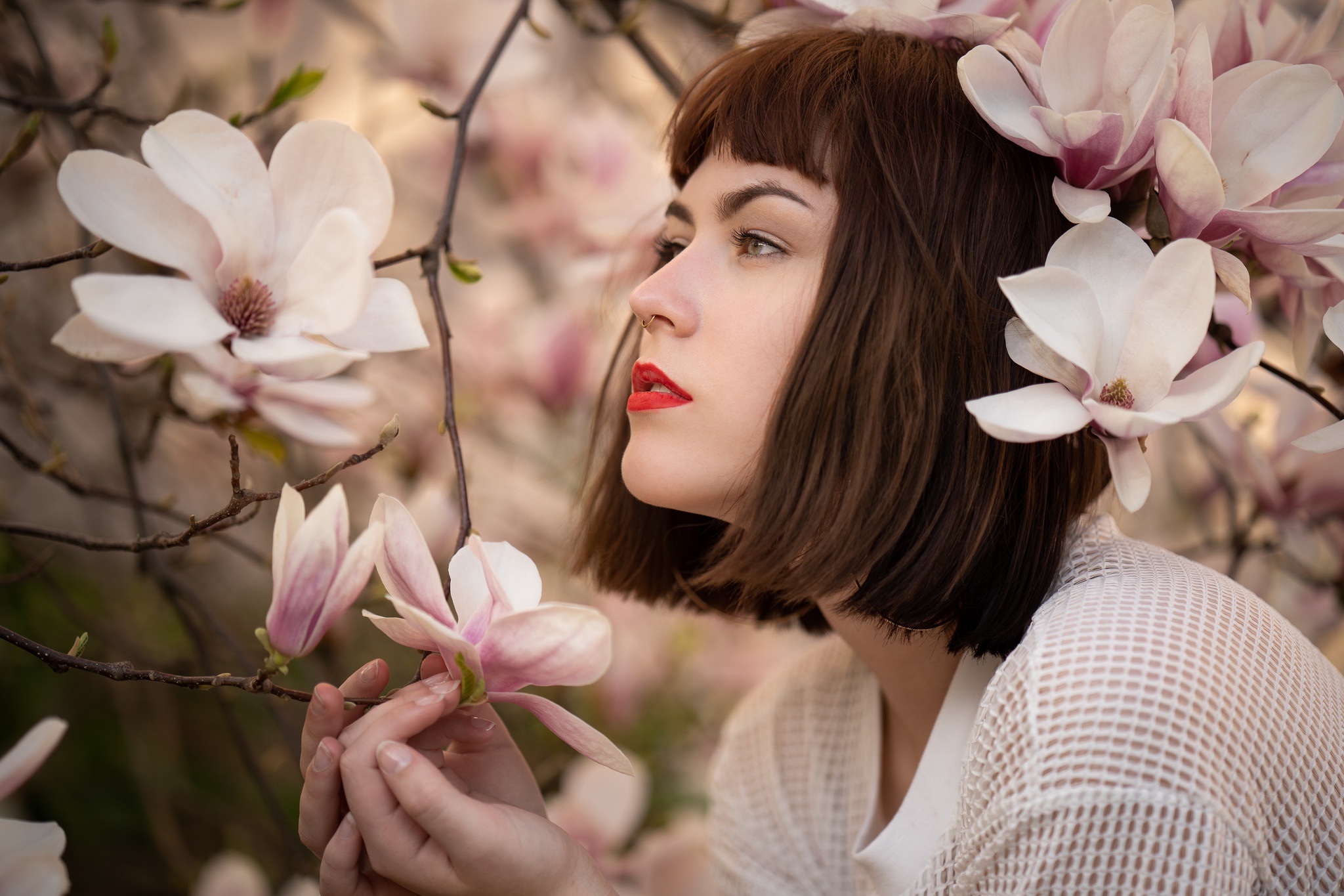 Woman with short brown hair and red lipstick among magnolia blossoms HD Wallpaper