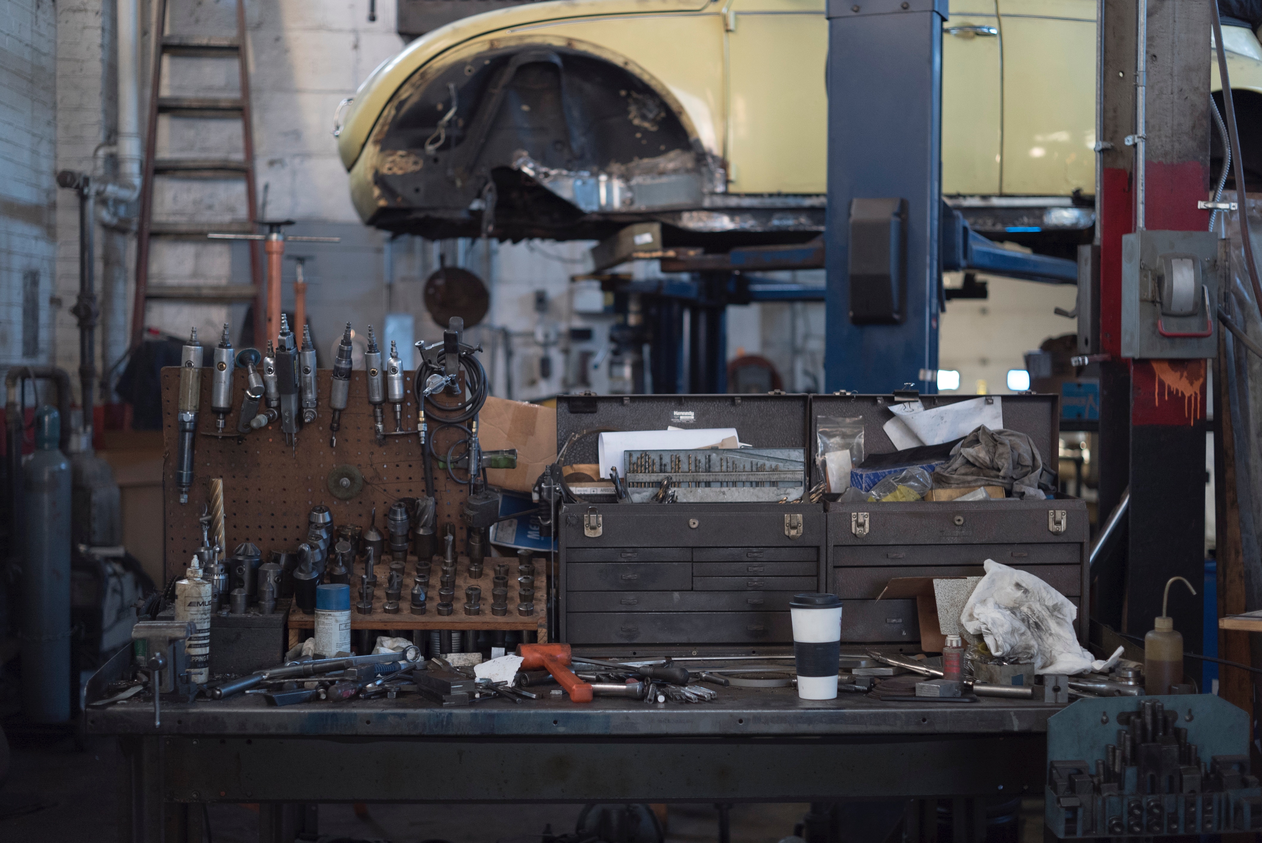Car repair shop with tools and car on lift HD Wallpaper
