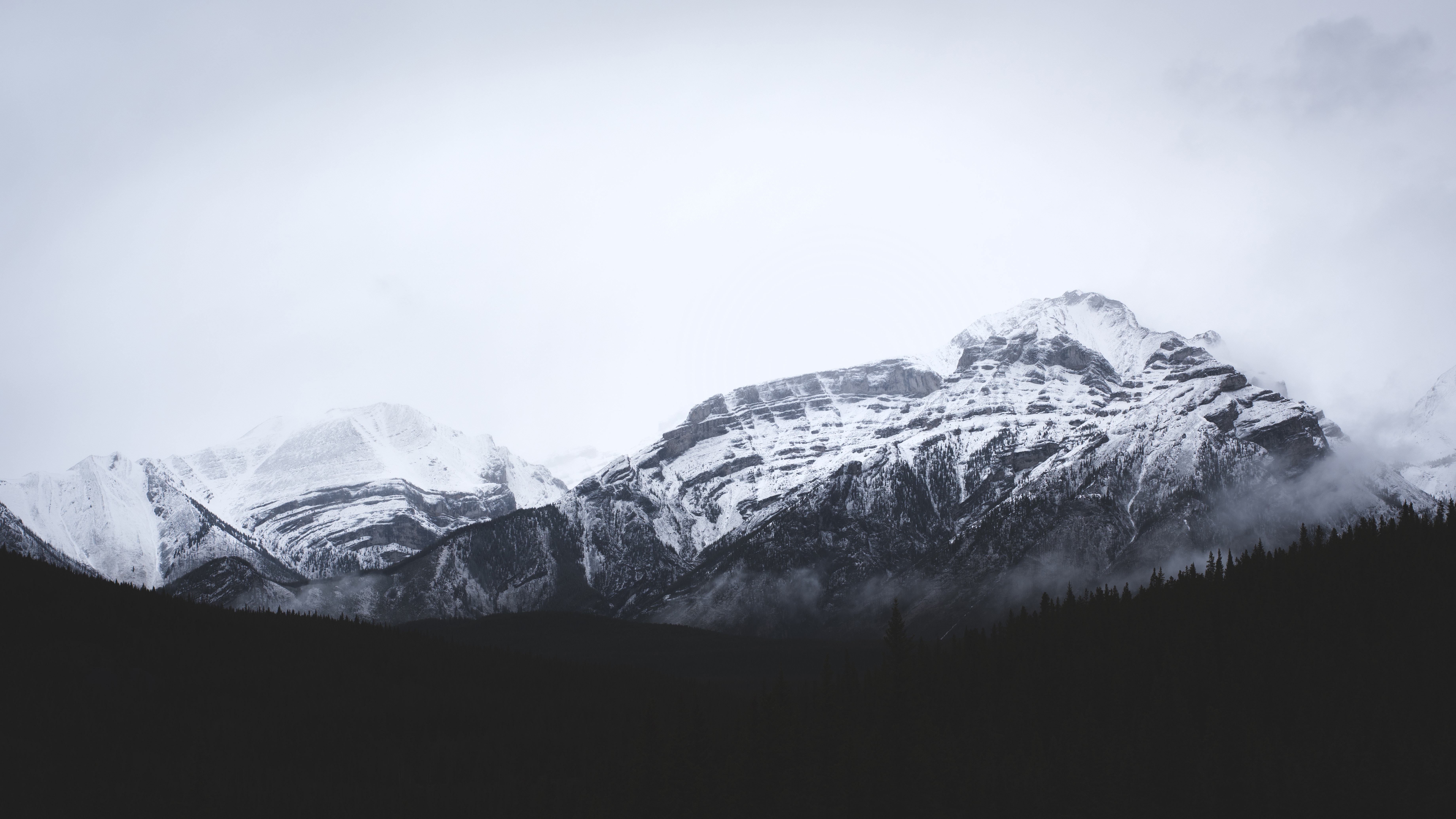 Snow-covered mountains in Banff under a cloudy sky HD Wallpaper