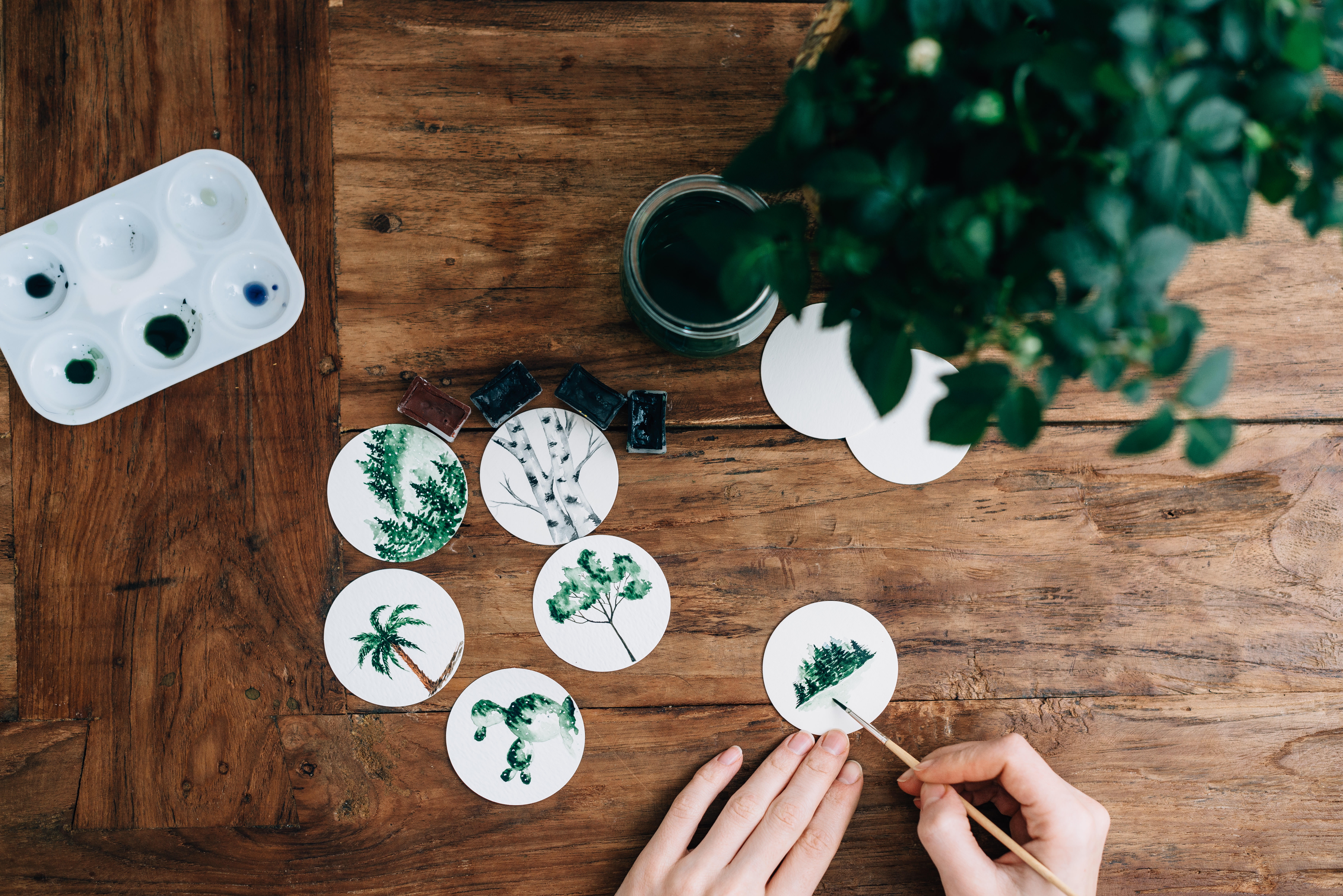 Person painting nature scenes on wooden table HD Wallpaper