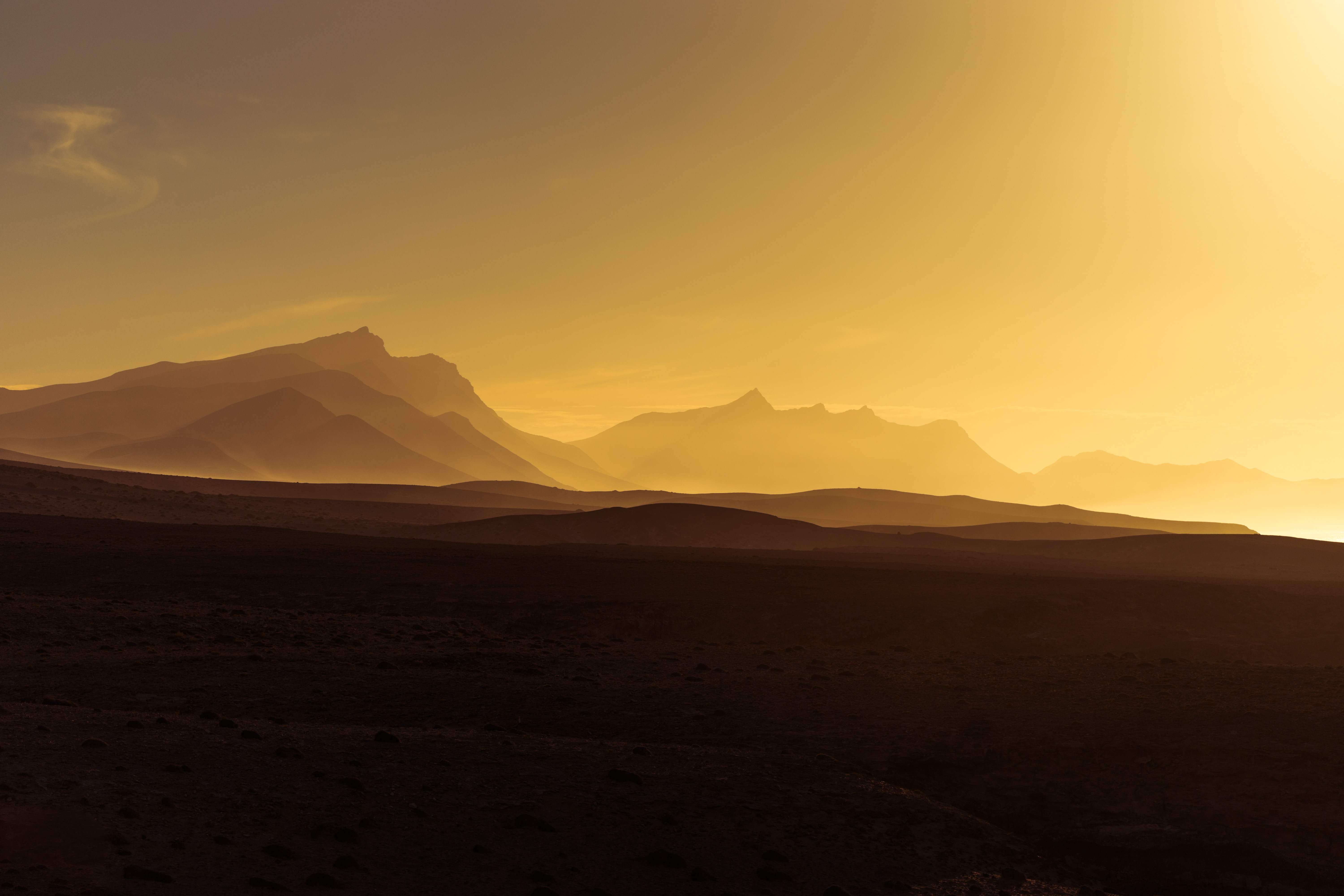 Mountain range silhouetted against a golden sunset sky HD Wallpaper