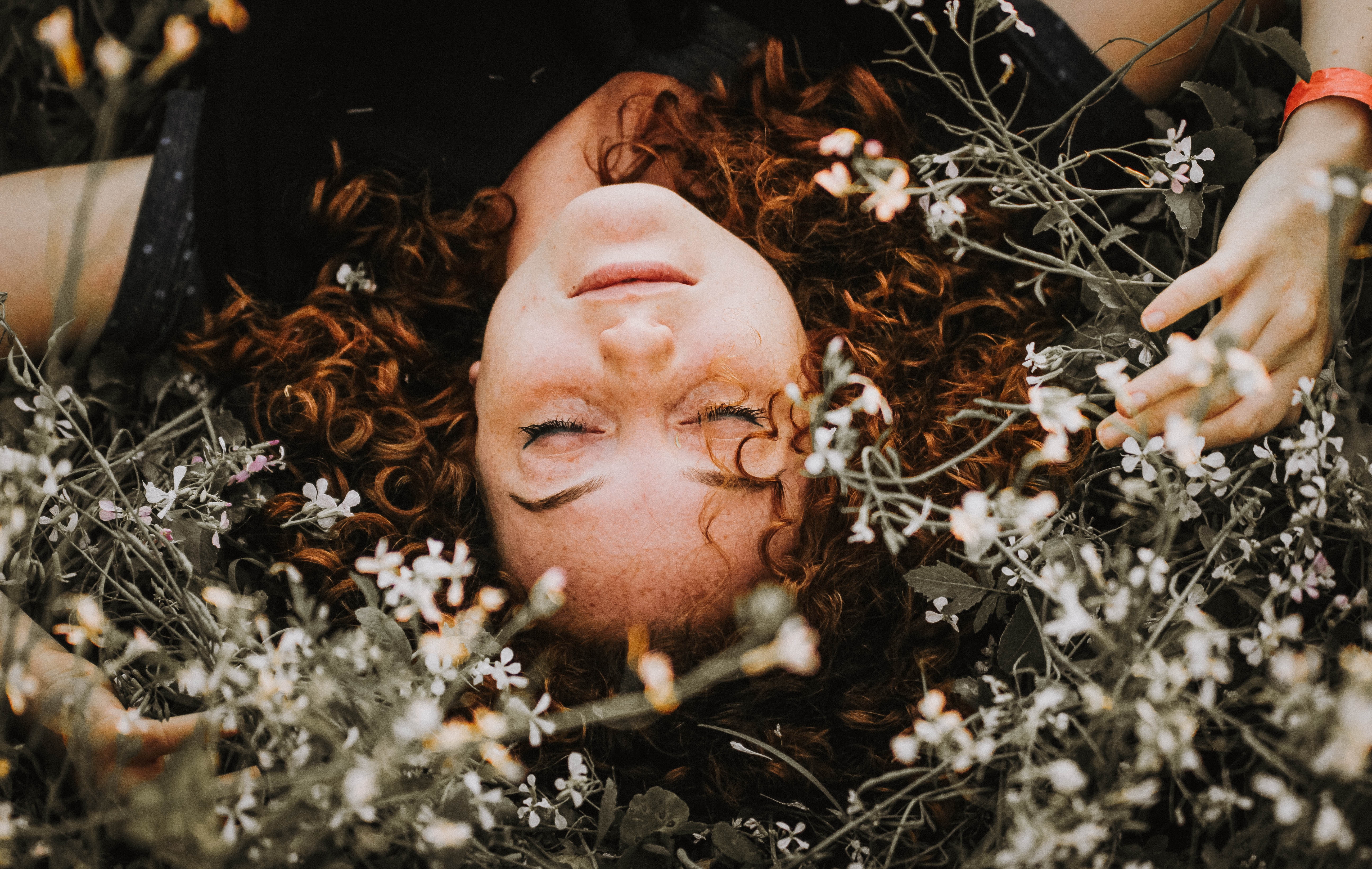 Redhead woman resting among flowers HD Wallpaper