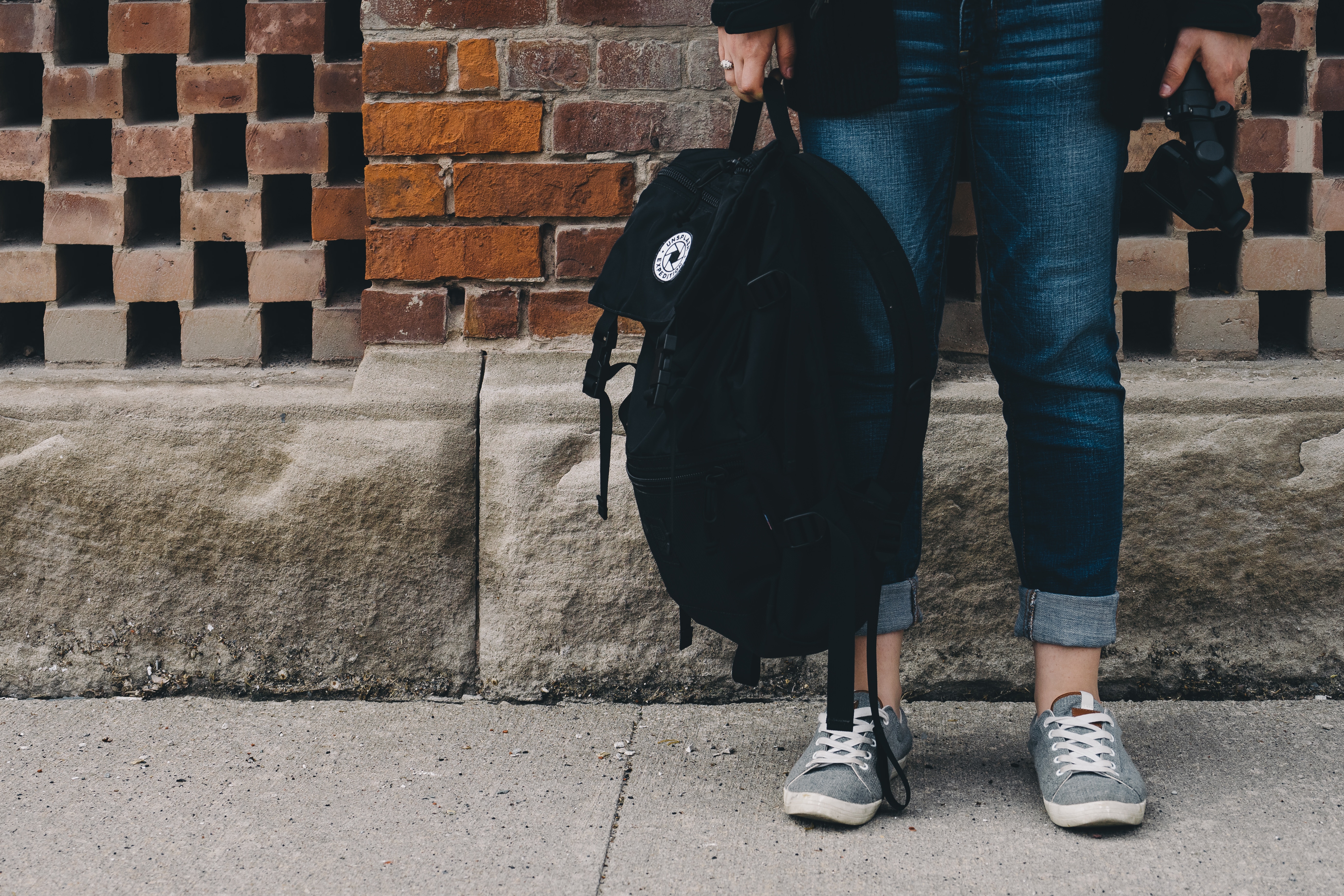 Person holding a black backpack and camera HD Wallpaper