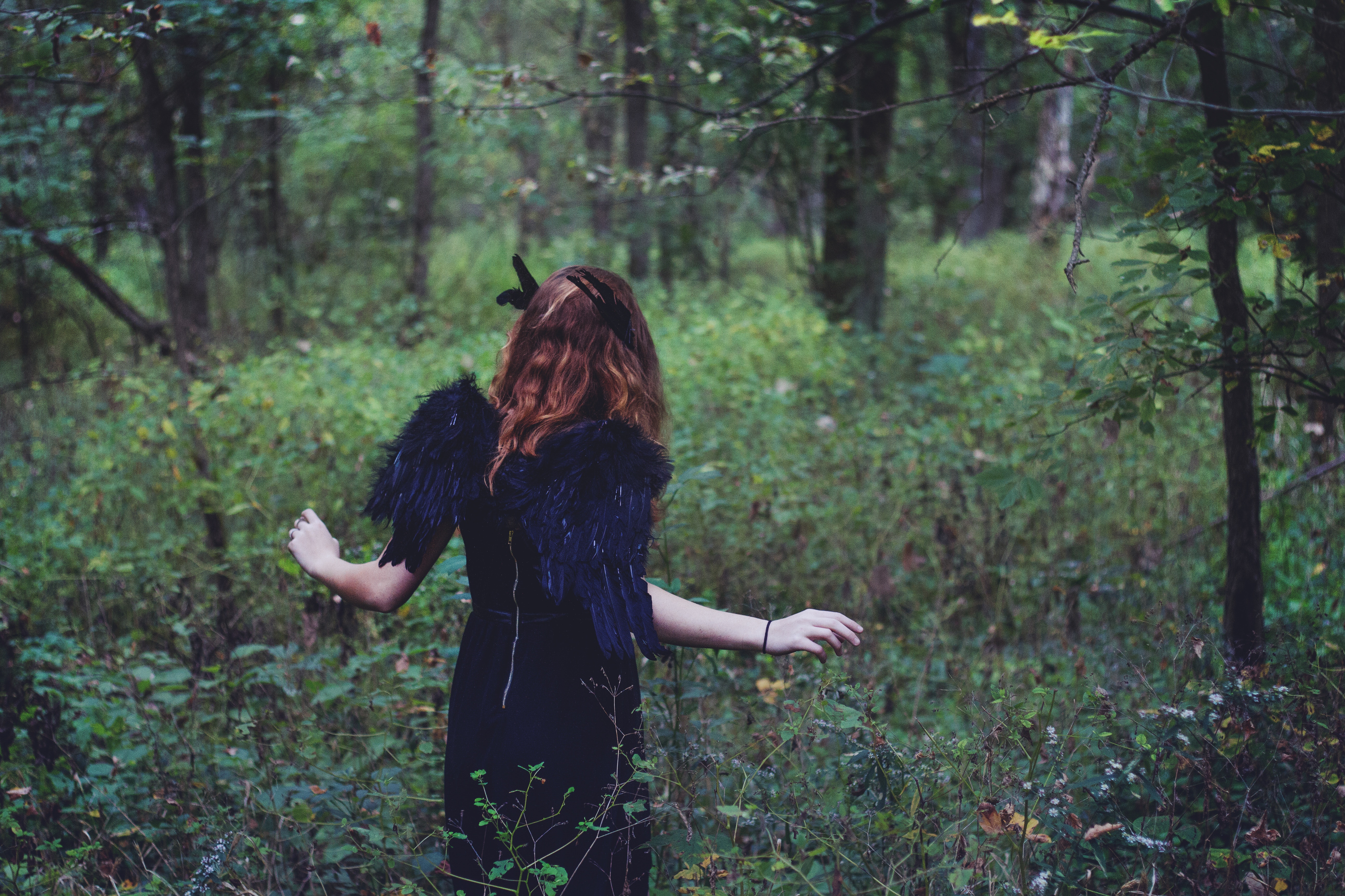 Woman in black dress with black wings in forest HD Wallpaper