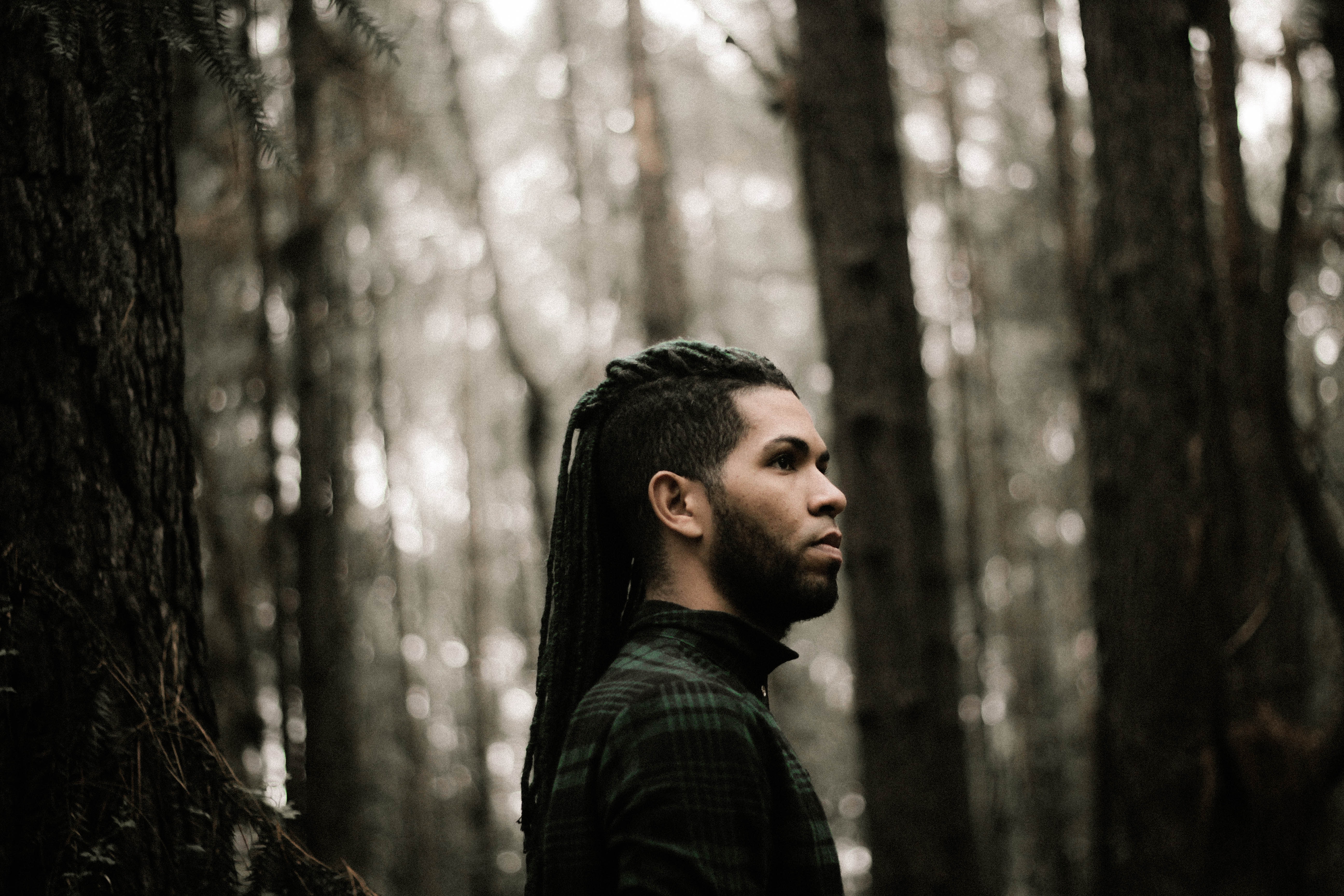 Man with dreadlocks in a forest HD Wallpaper