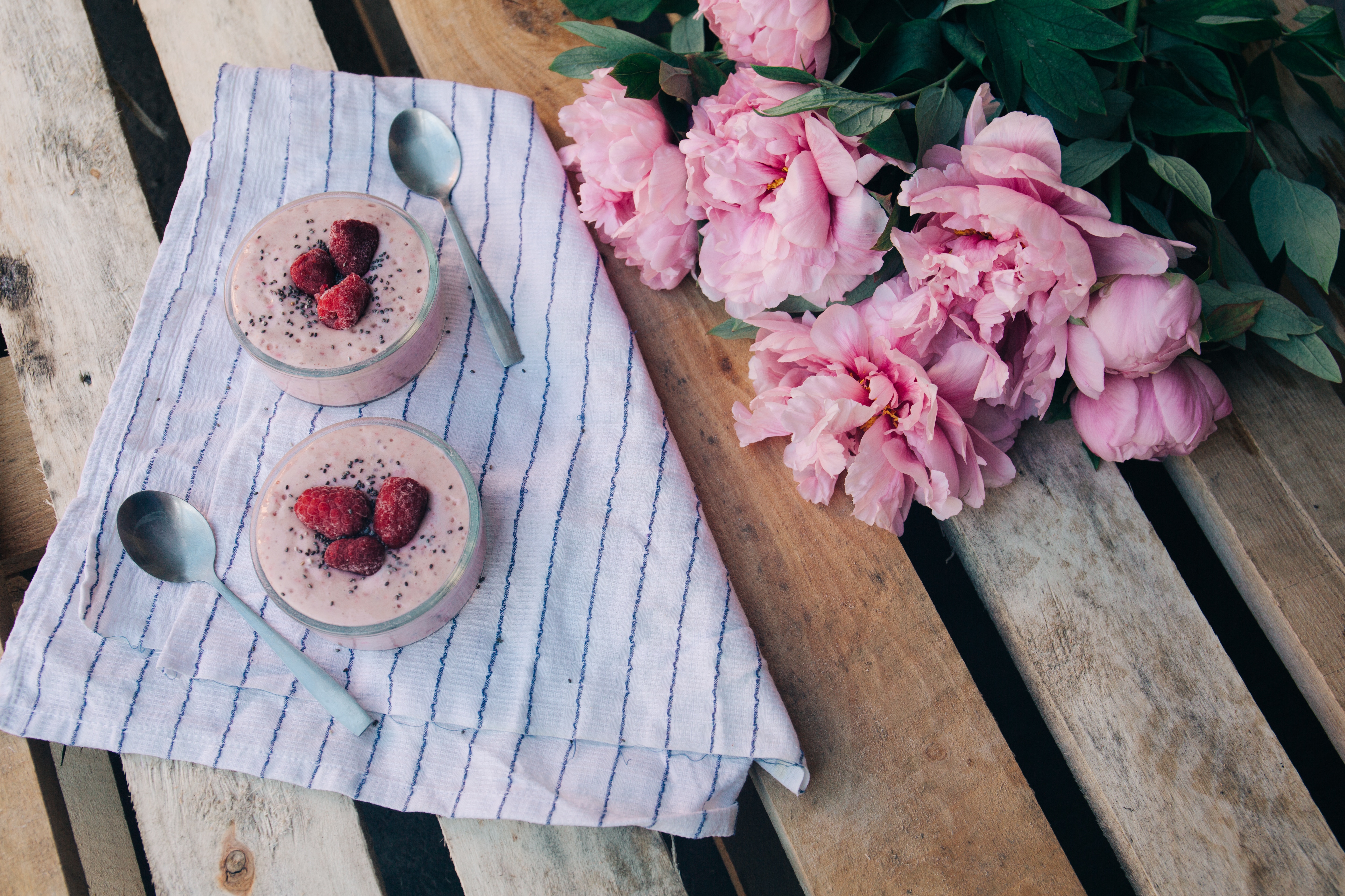 Two smoothies with raspberries and peonies on a wooden table HD Wallpaper