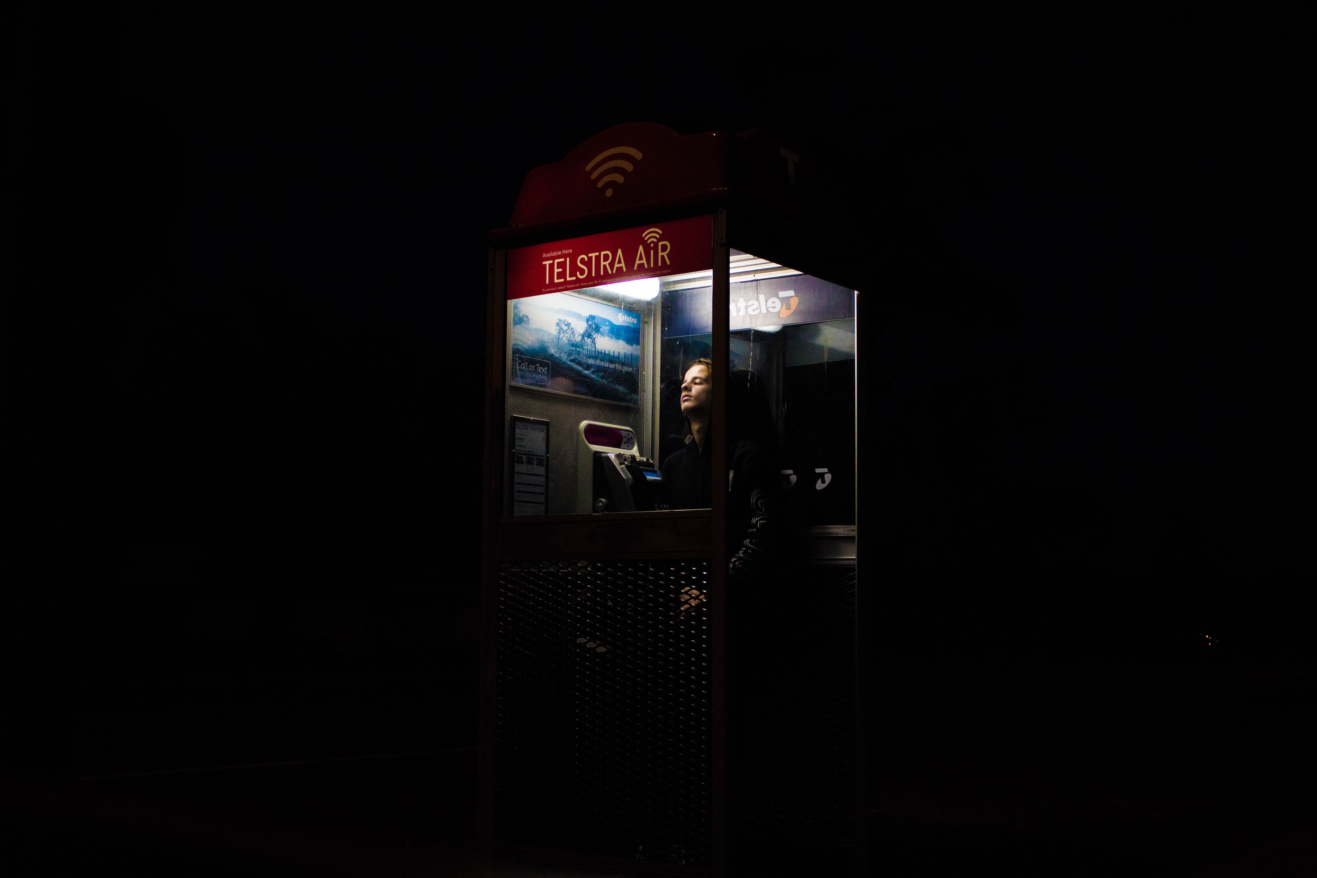 Person in a Telstra Air phone booth at night HD Wallpaper