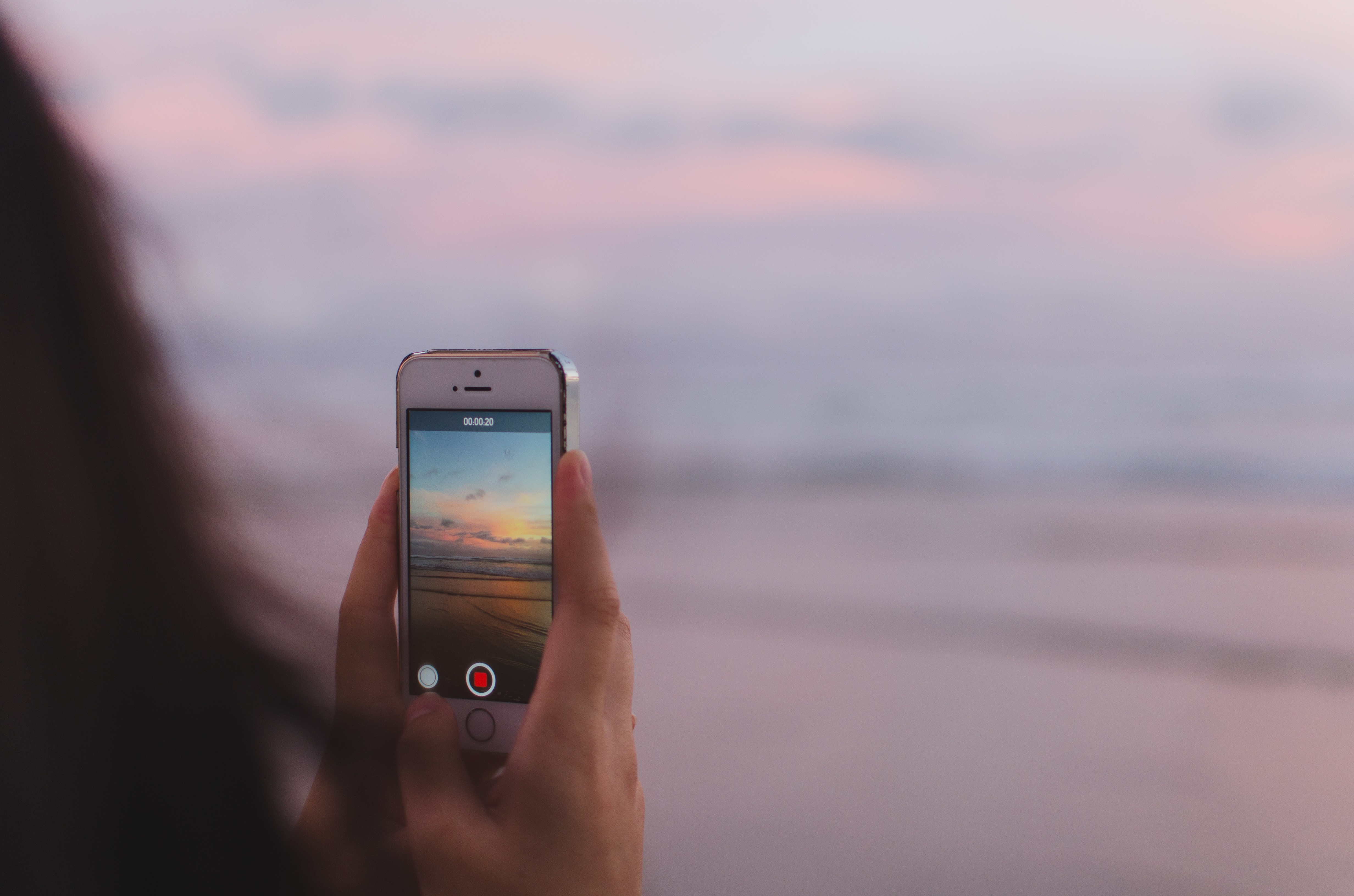Person holding iPhone recording a sunset at the beach HD Wallpaper