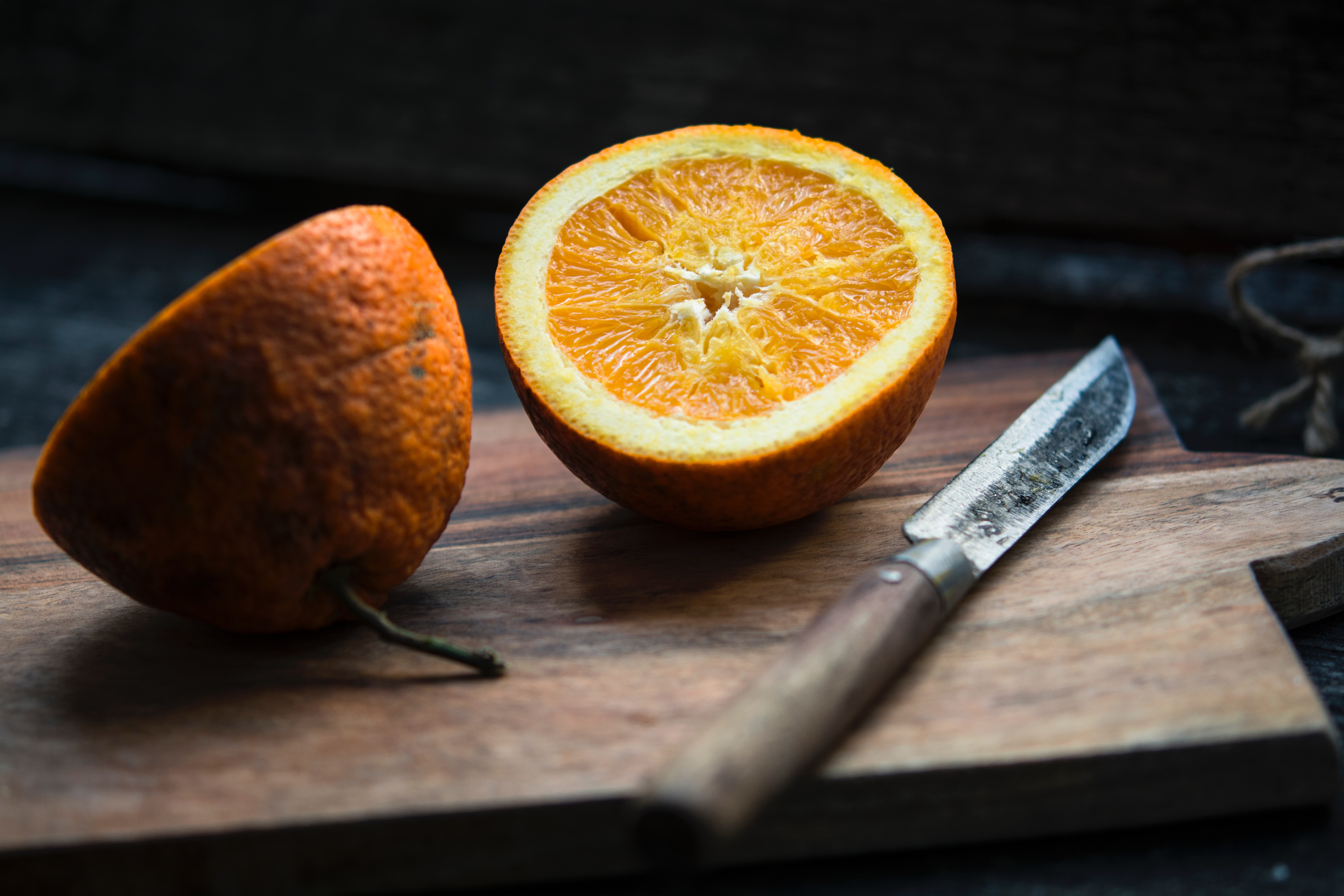 Orange cut in half with a knife on a cutting board HD Wallpaper