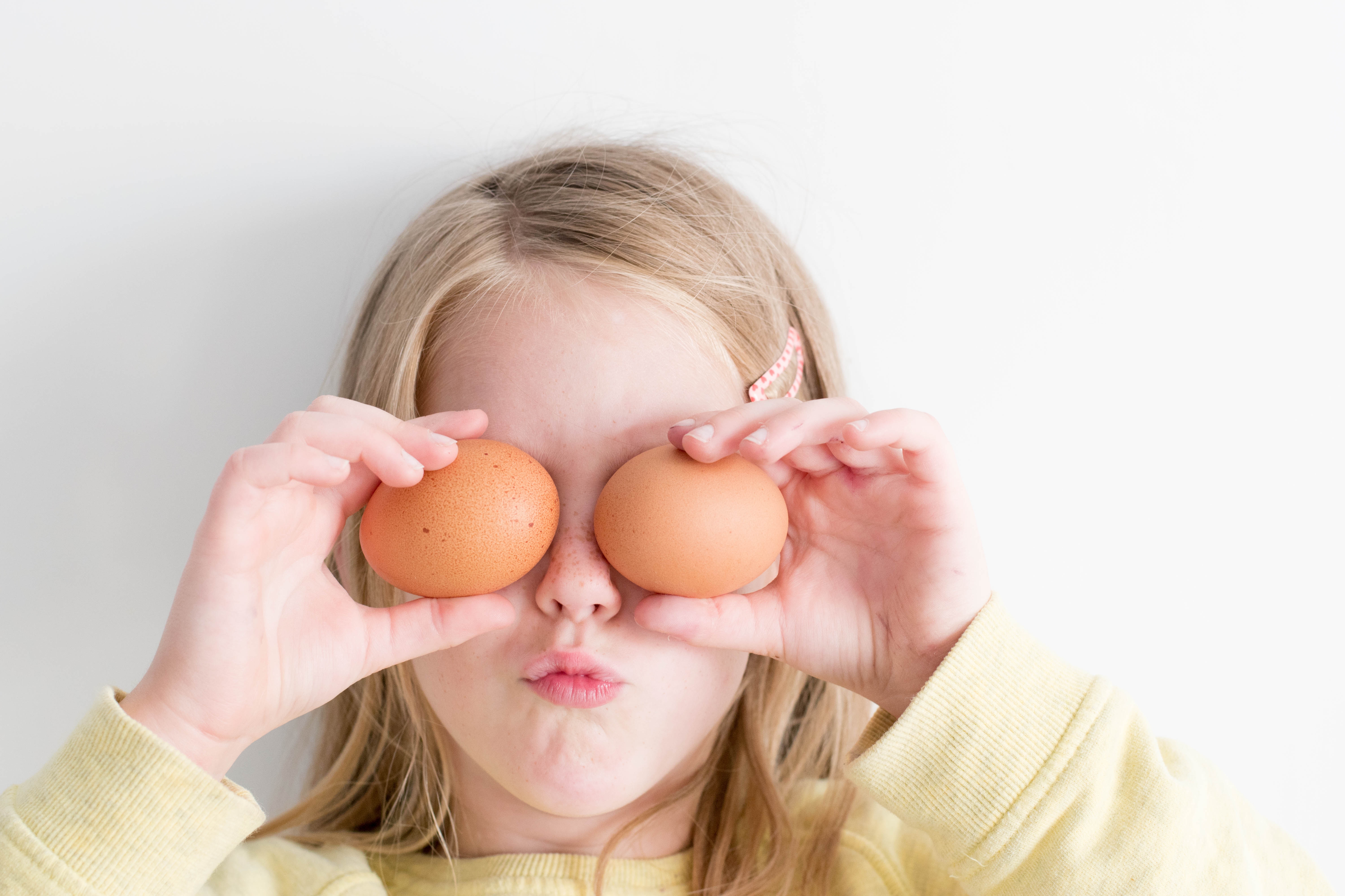 Girl holding eggs over her eyes HD Wallpaper