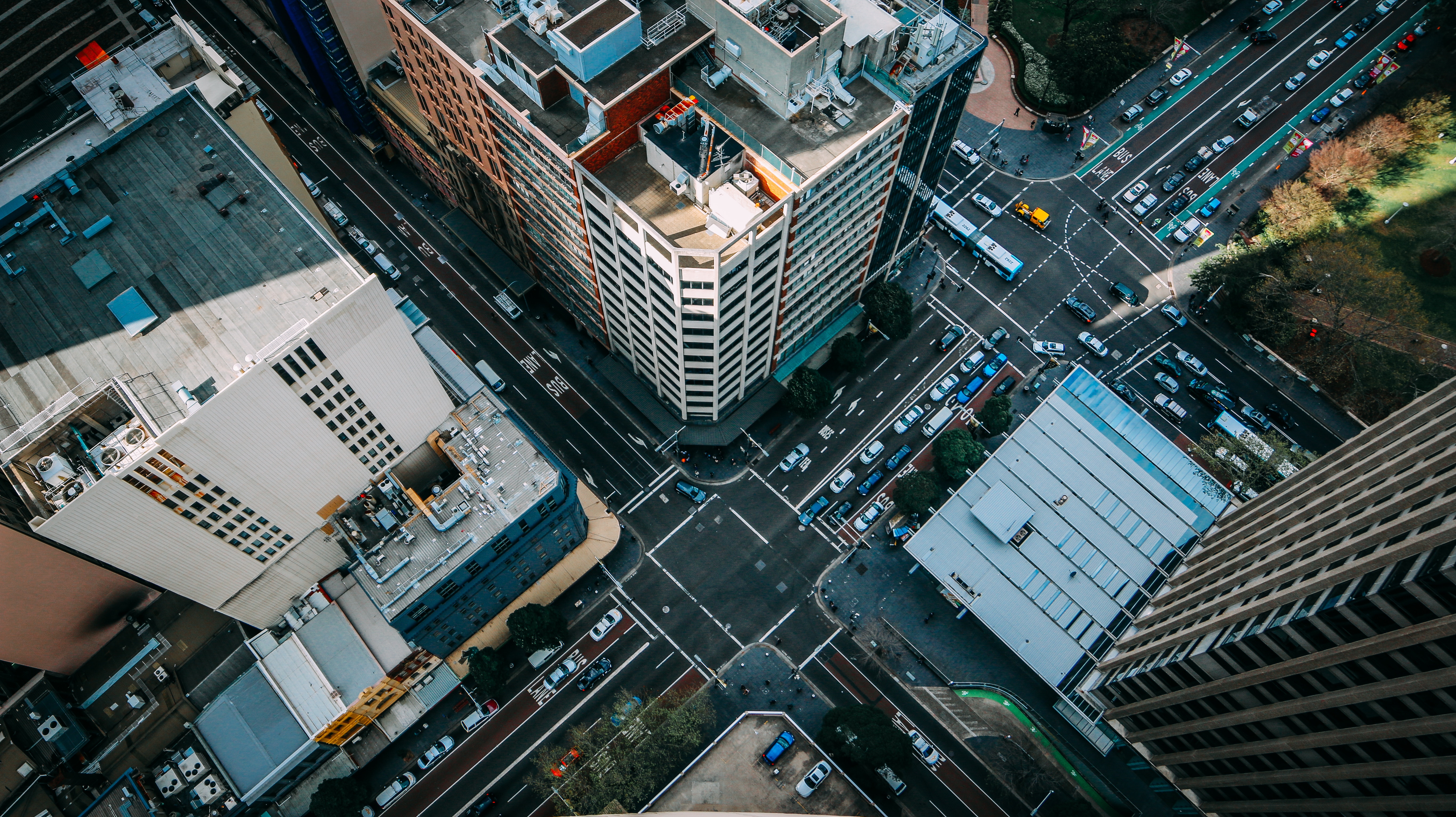 Aerial view of a busy city intersection with traffic and buildings HD Wallpaper