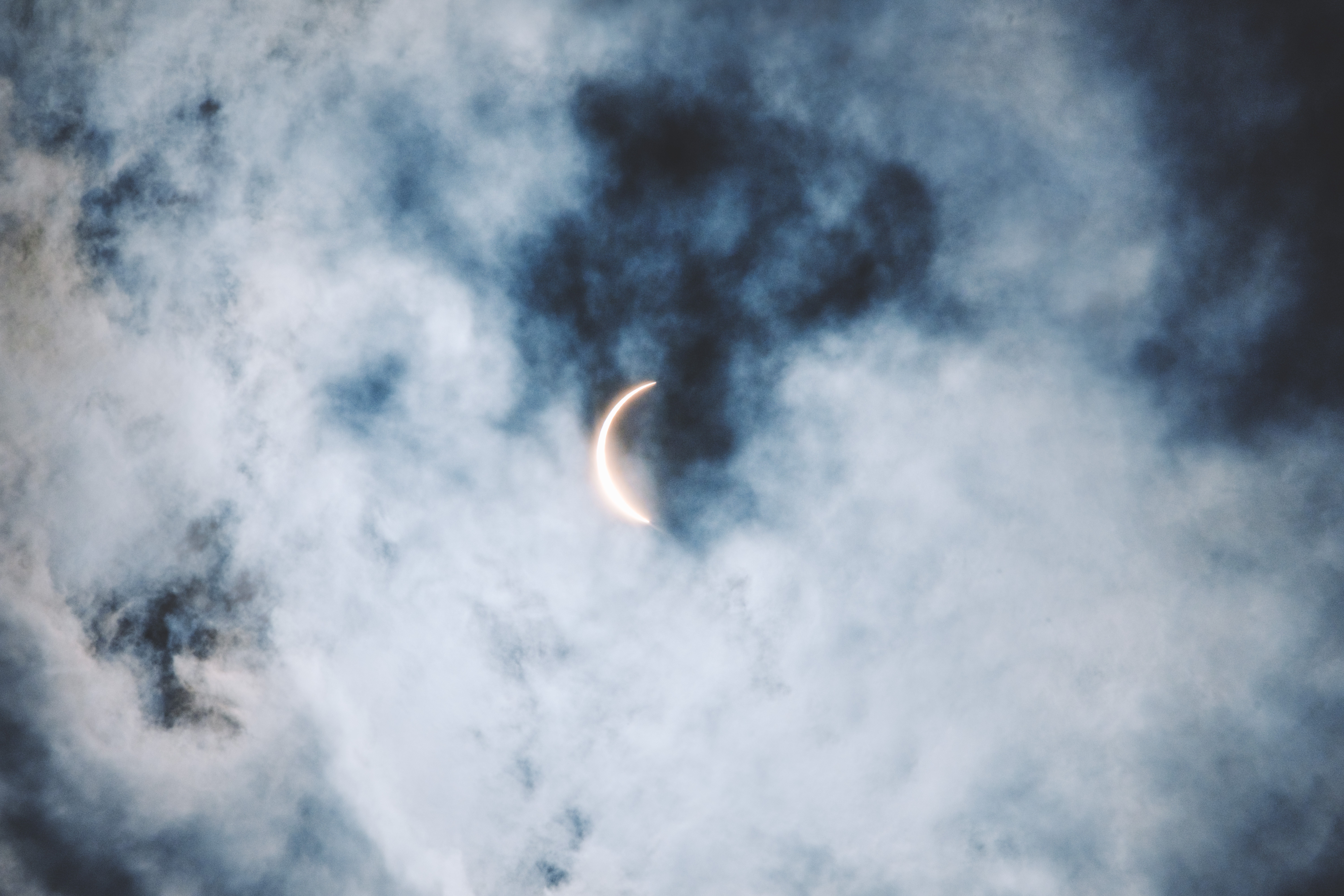 Crescent sun during a solar eclipse behind clouds HD Wallpaper