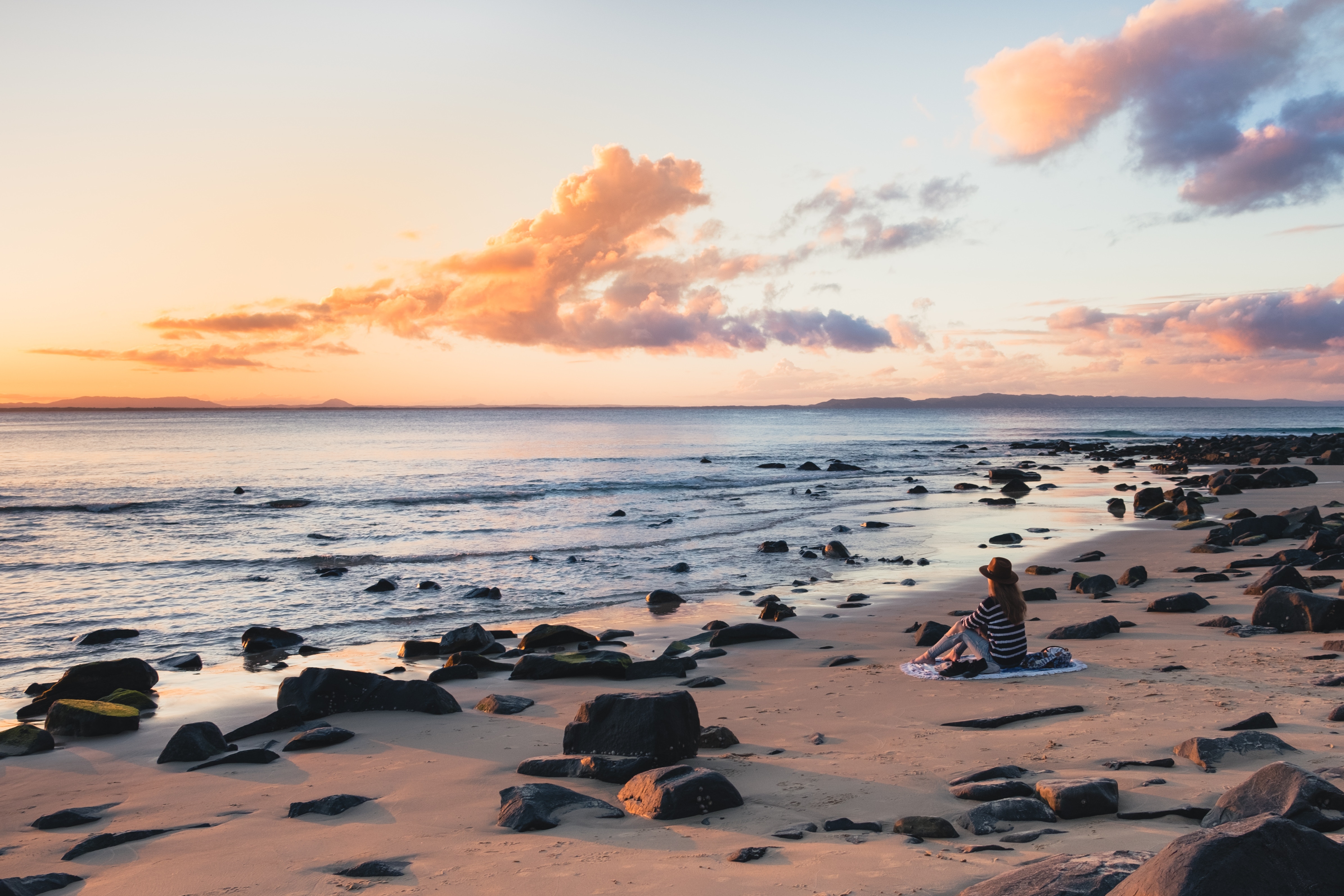 Woman sitting on a beach at sunset HD Wallpaper