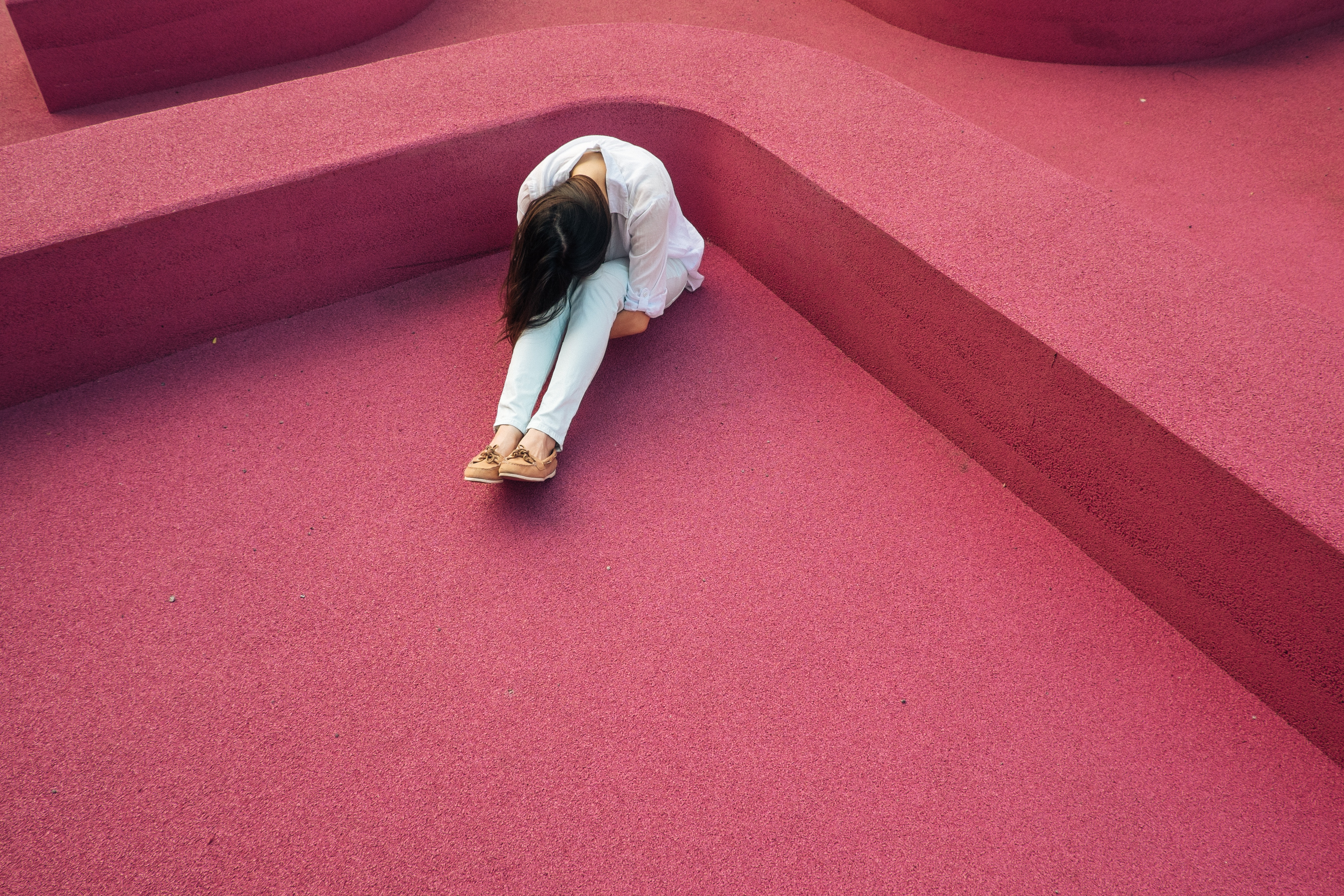Woman sitting alone on pink ground HD Wallpaper