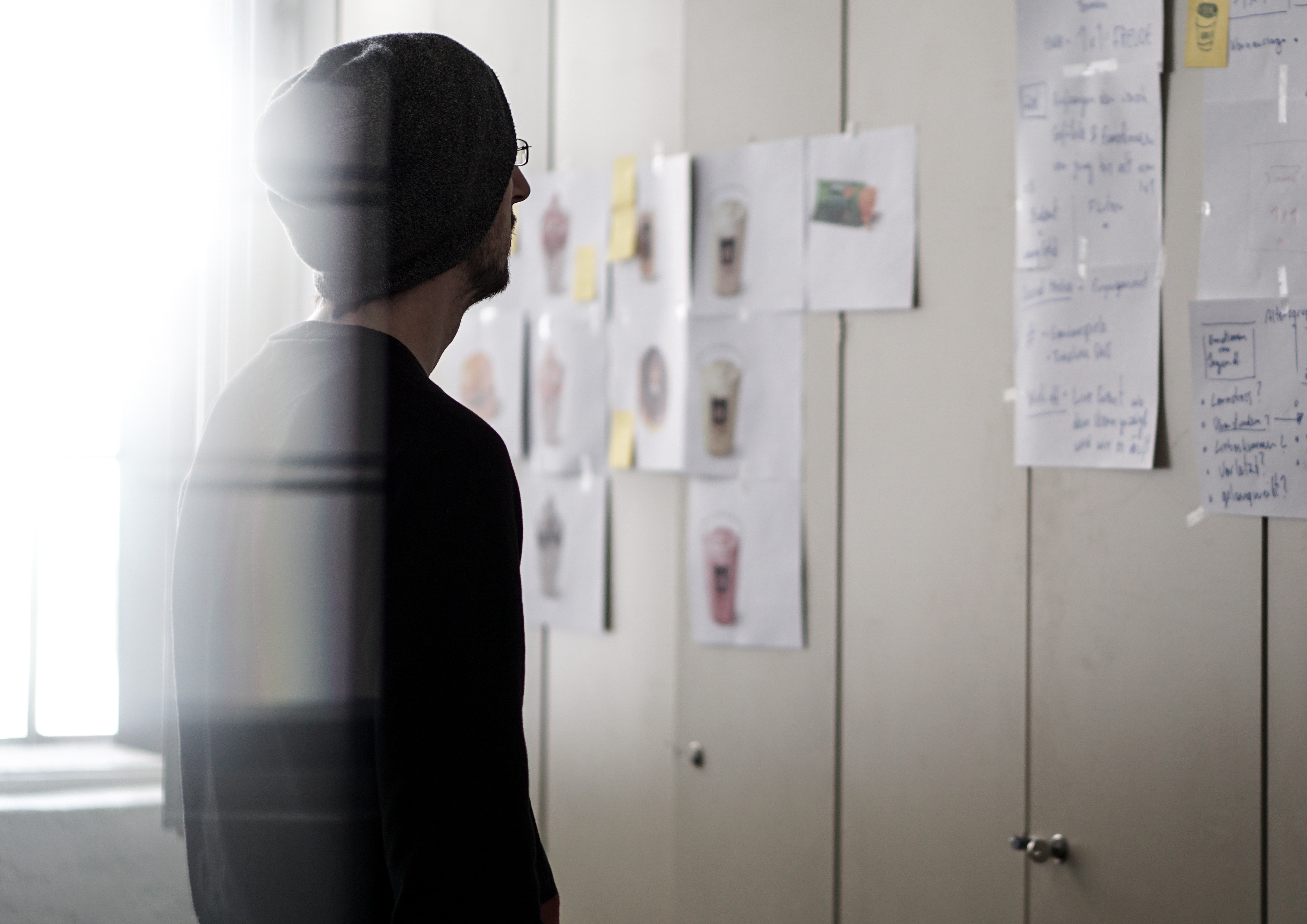 Man in beanie looking at design sketches on wall HD Wallpaper