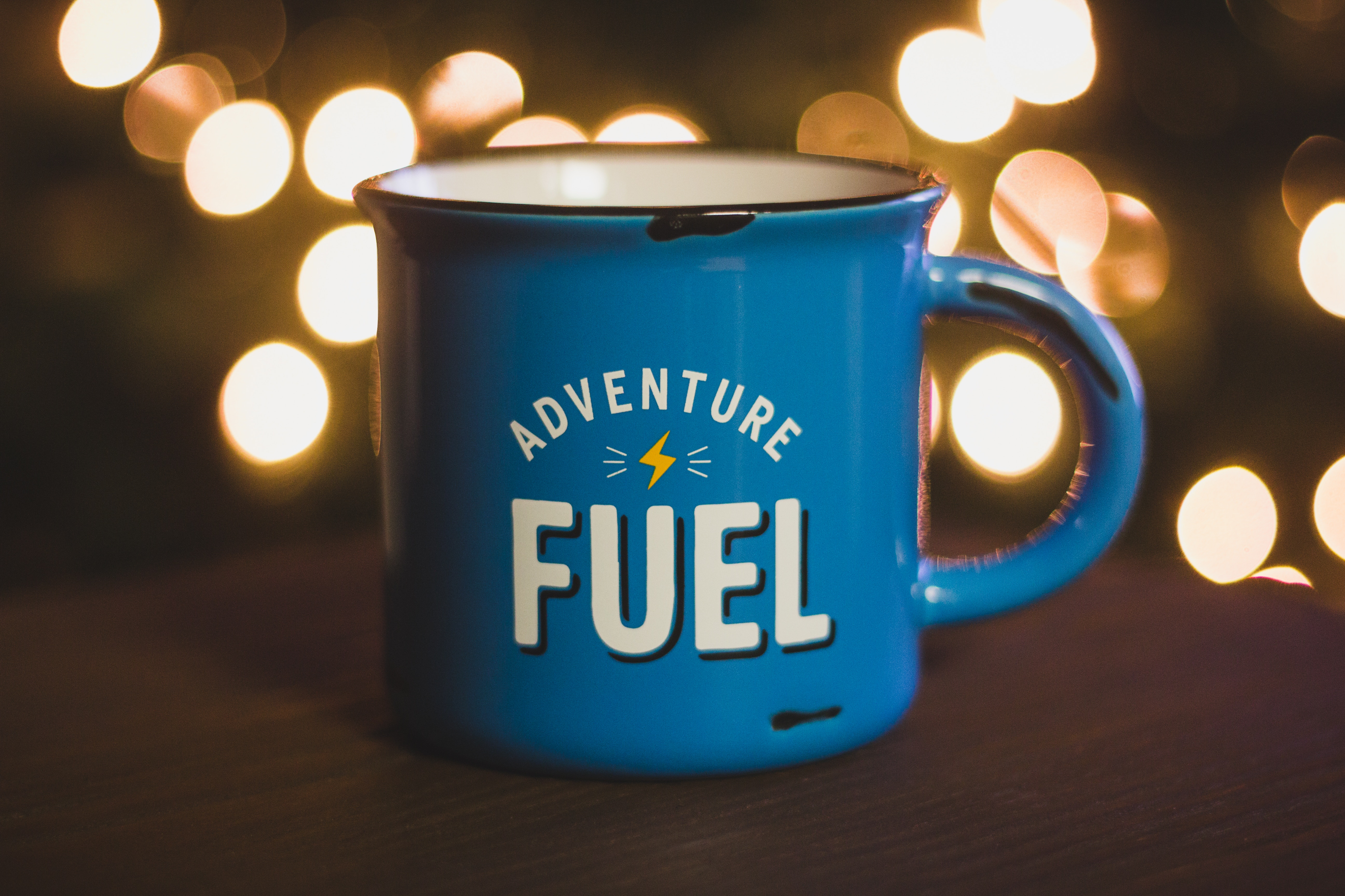 Blue mug with "Adventure Fuel" text and bokeh lights HD Wallpaper