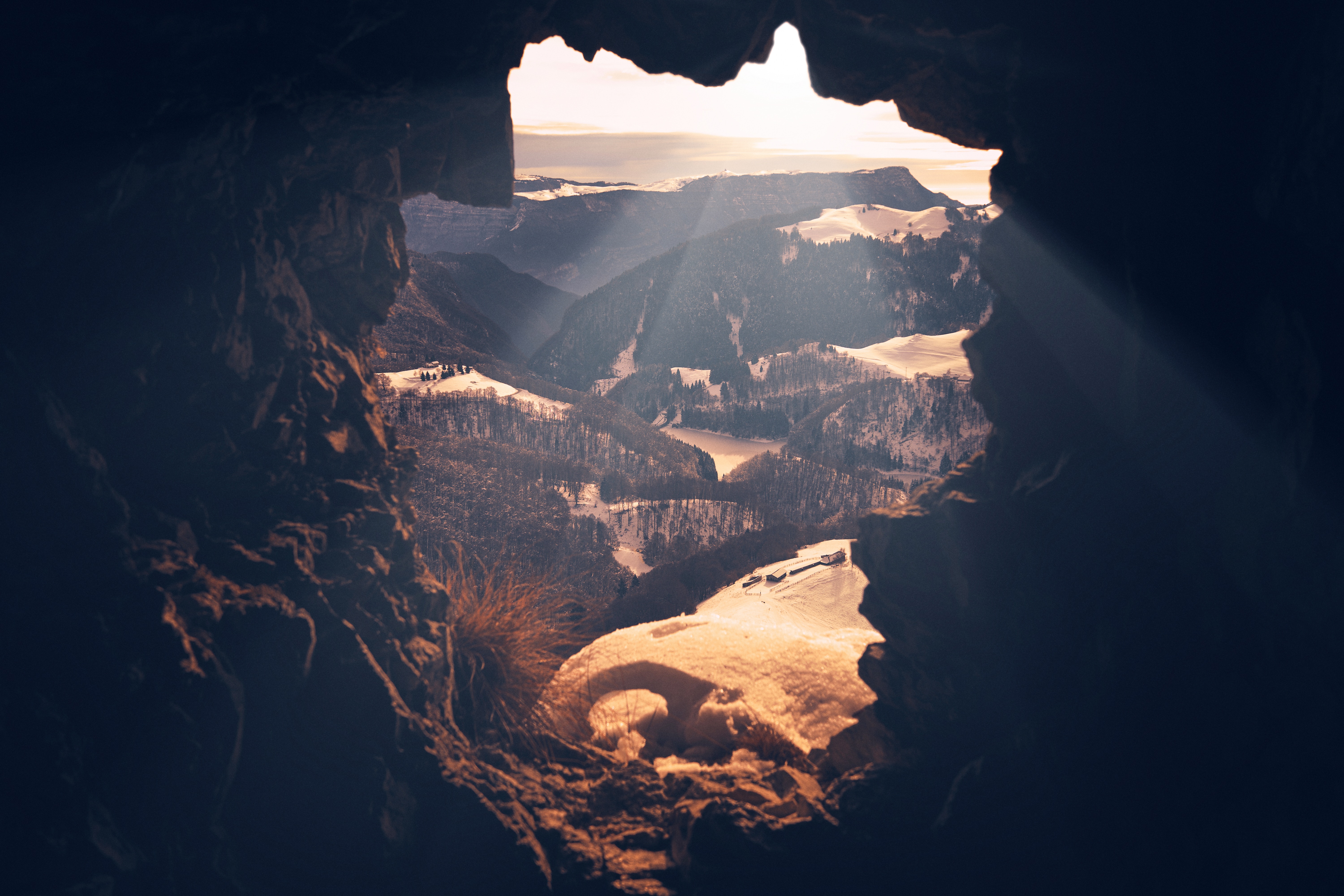 View of snowy mountains from a cave entrance HD Wallpaper