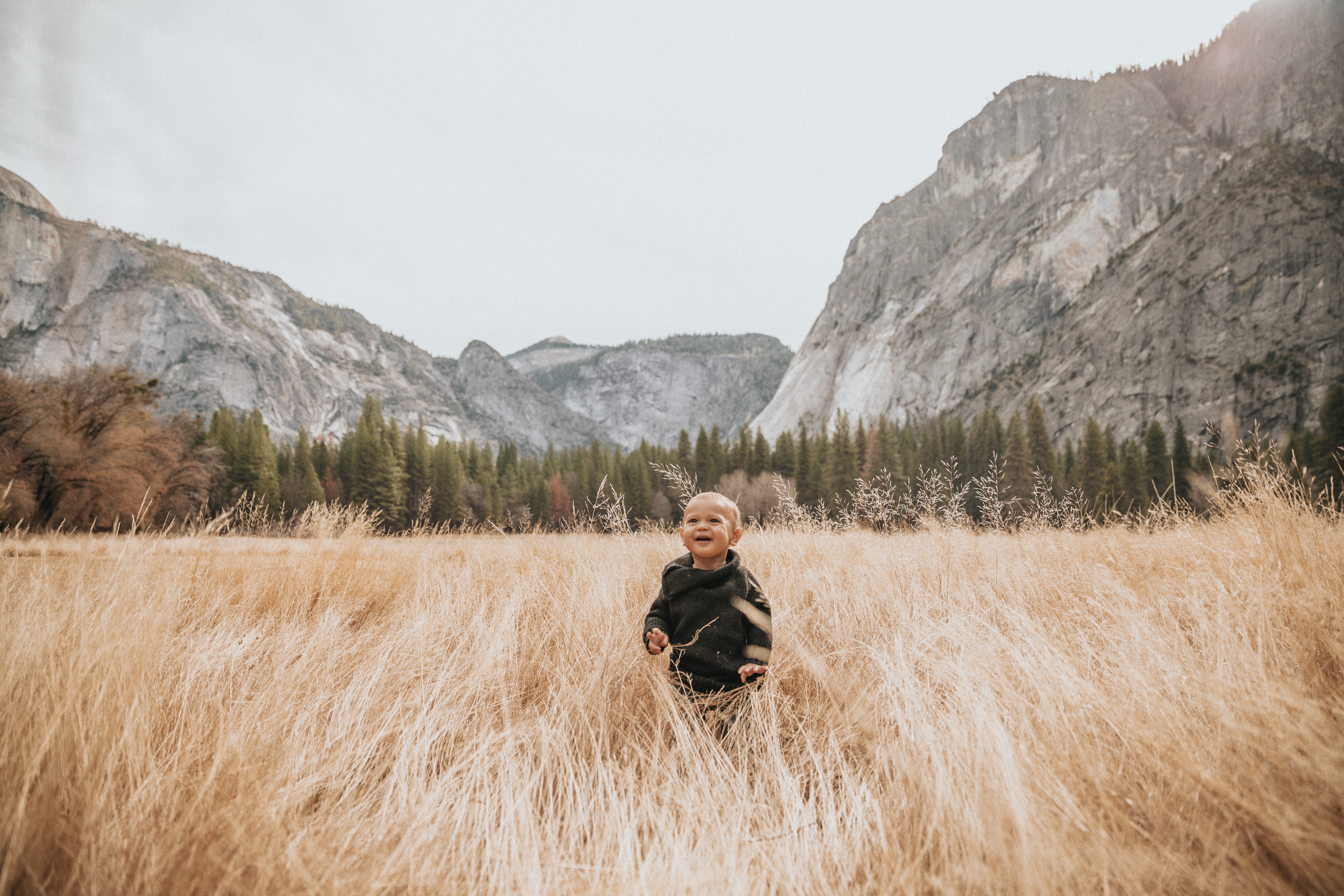 Baby boy in a field with mountains HD Wallpaper