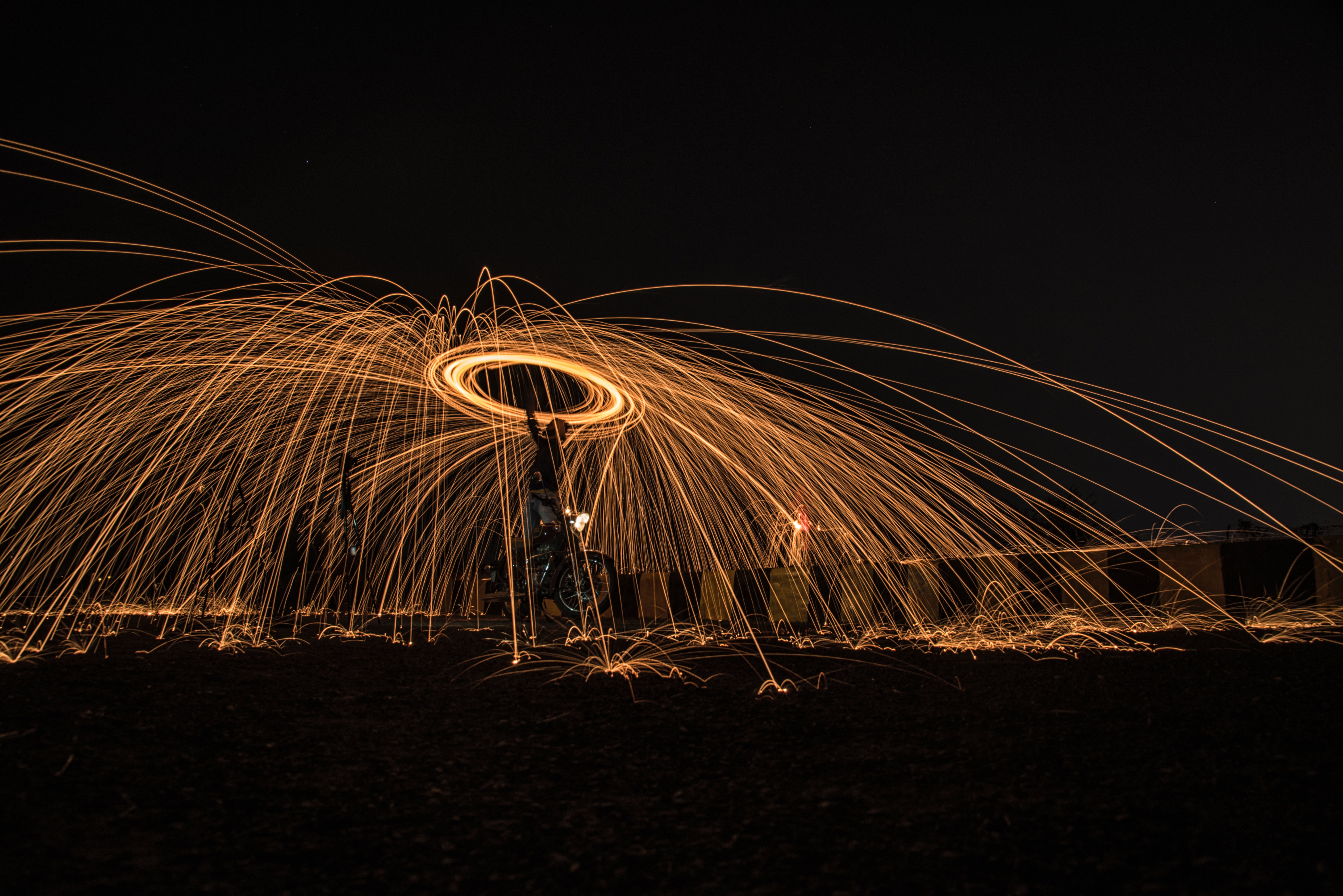 Man performing steel wool photography with a bike at night HD Wallpaper