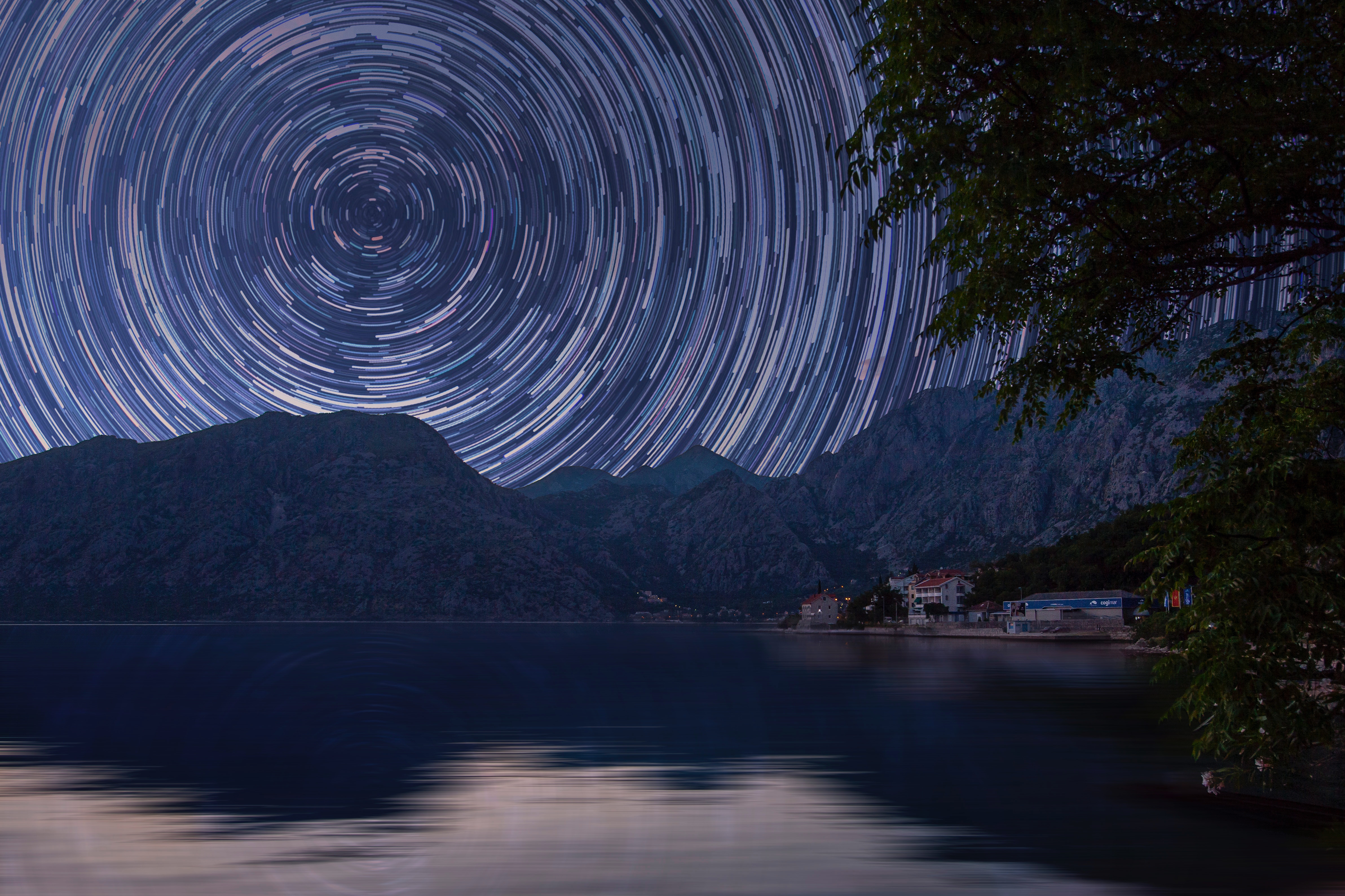 Star trails over mountains and water at night HD Wallpaper