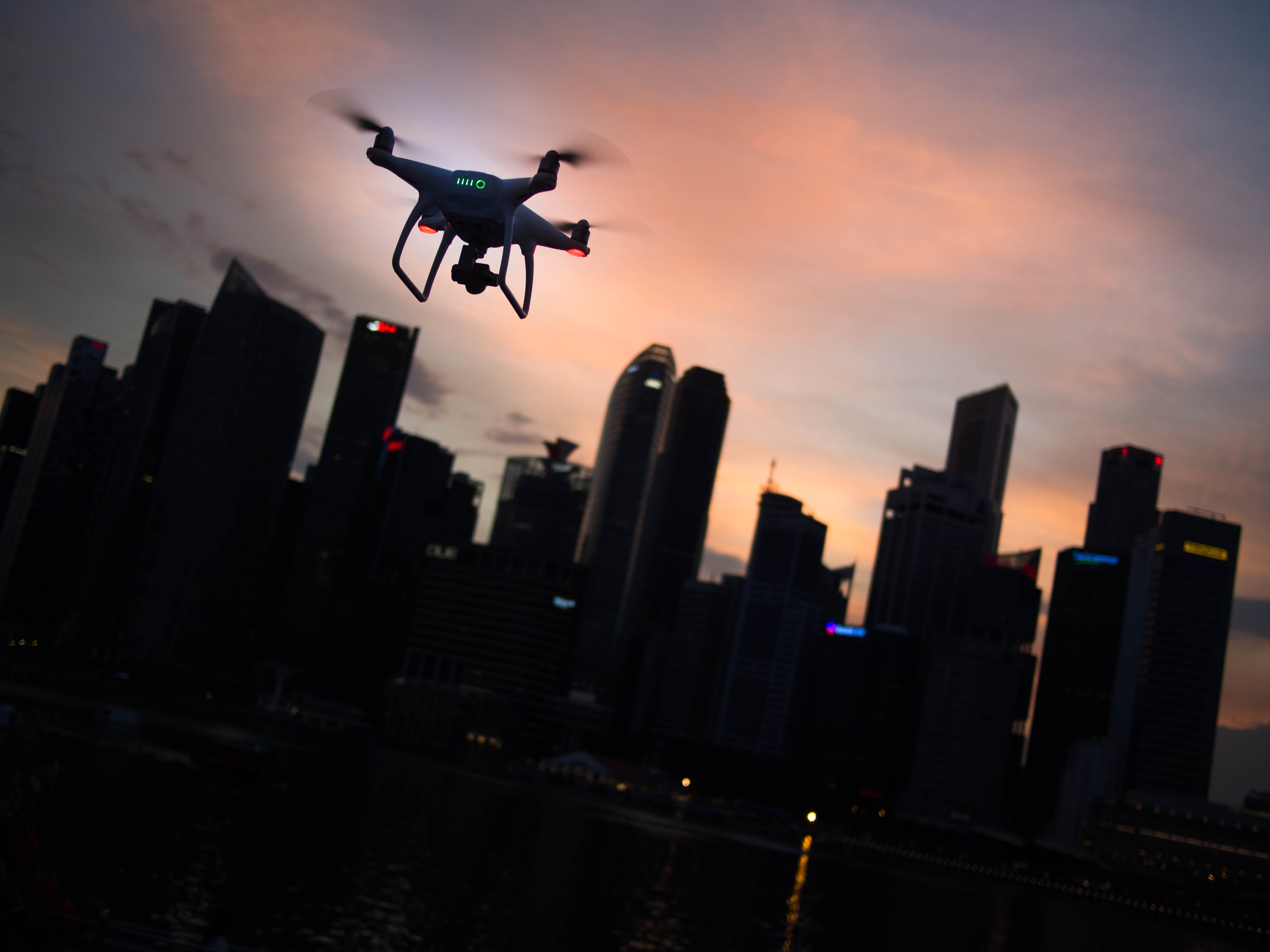 Drone flying over city skyline at sunset HD Wallpaper
