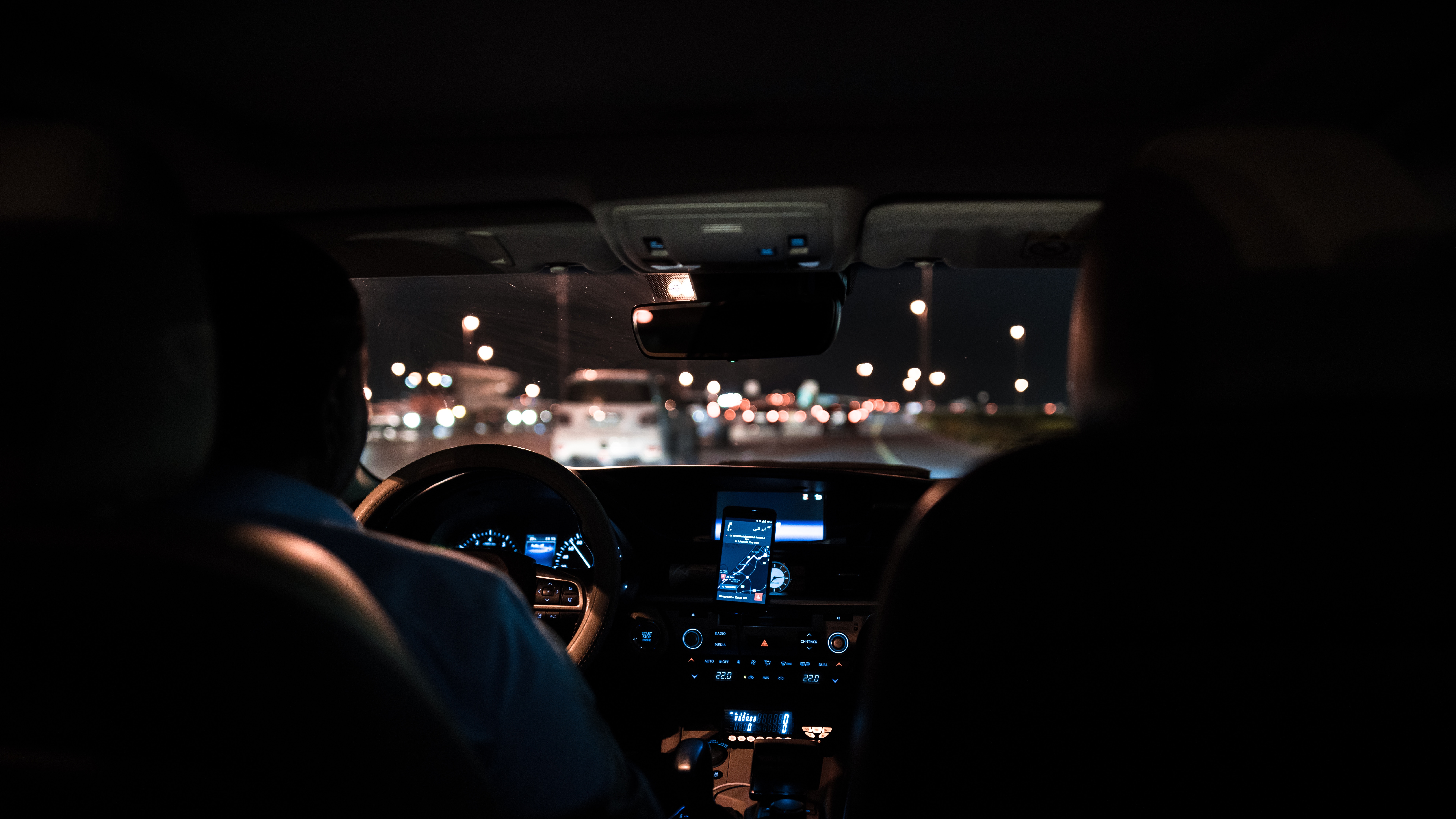 Two people in a car at night with city lights HD Wallpaper