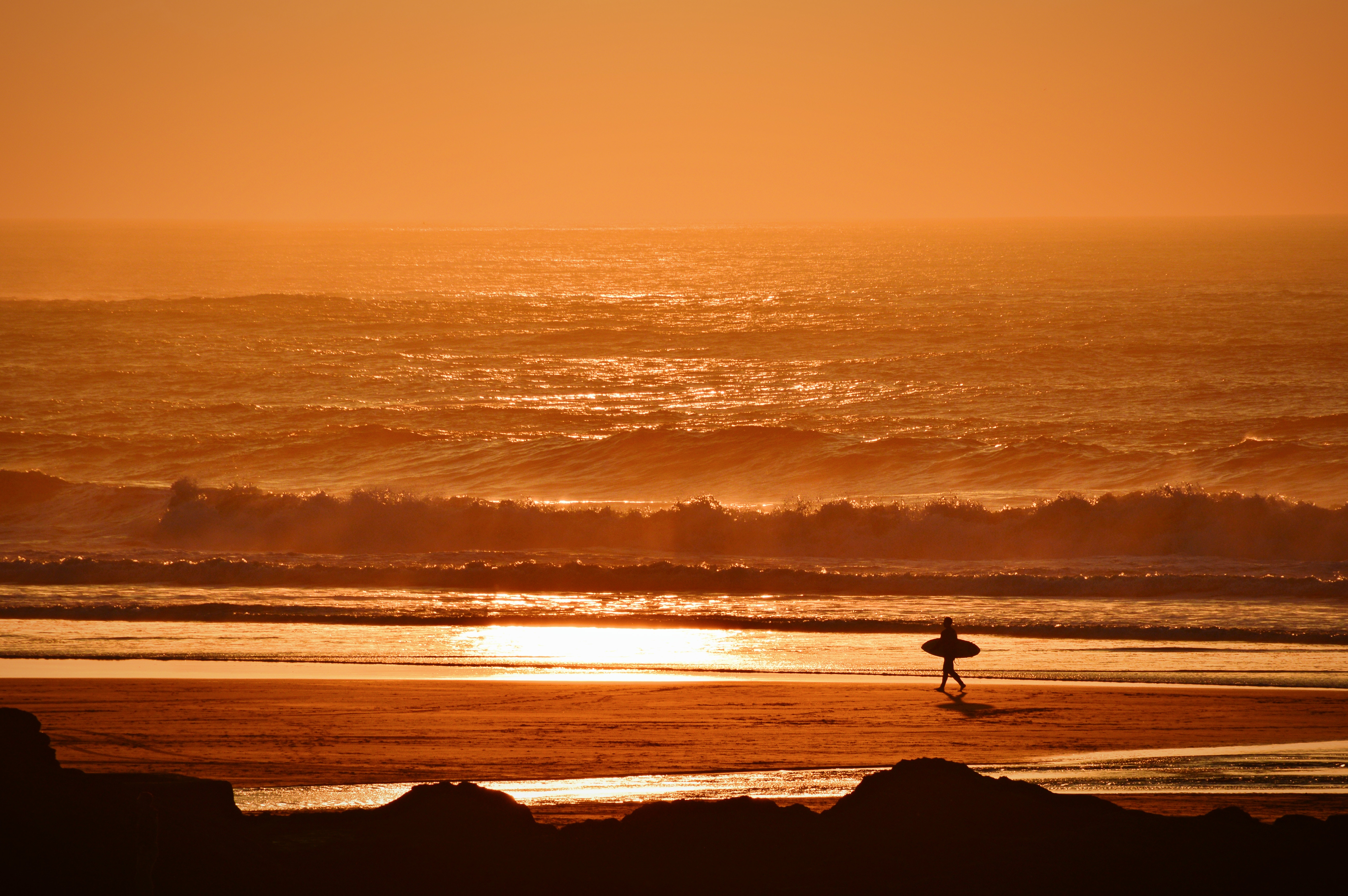 Surfer walking on beach at sunset in Cornwall HD Wallpaper