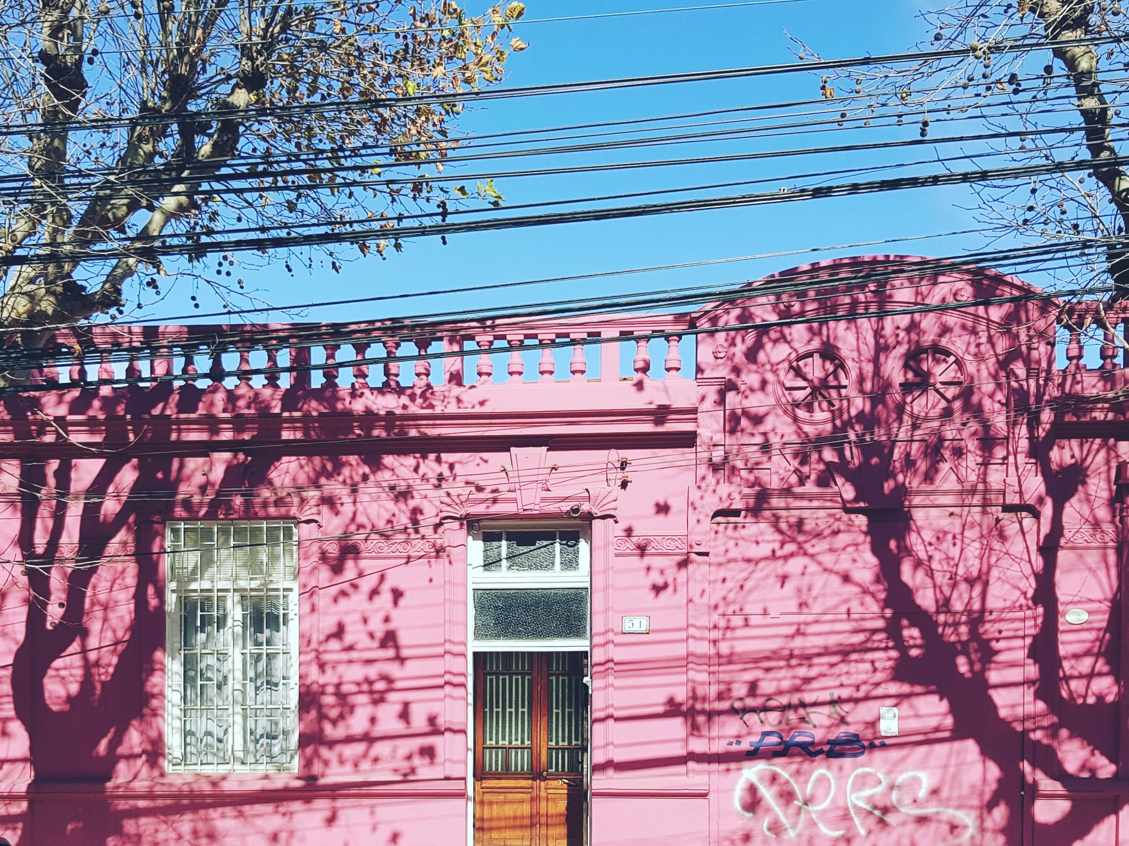 Pink house facade with tree shadows and power lines HD Wallpaper