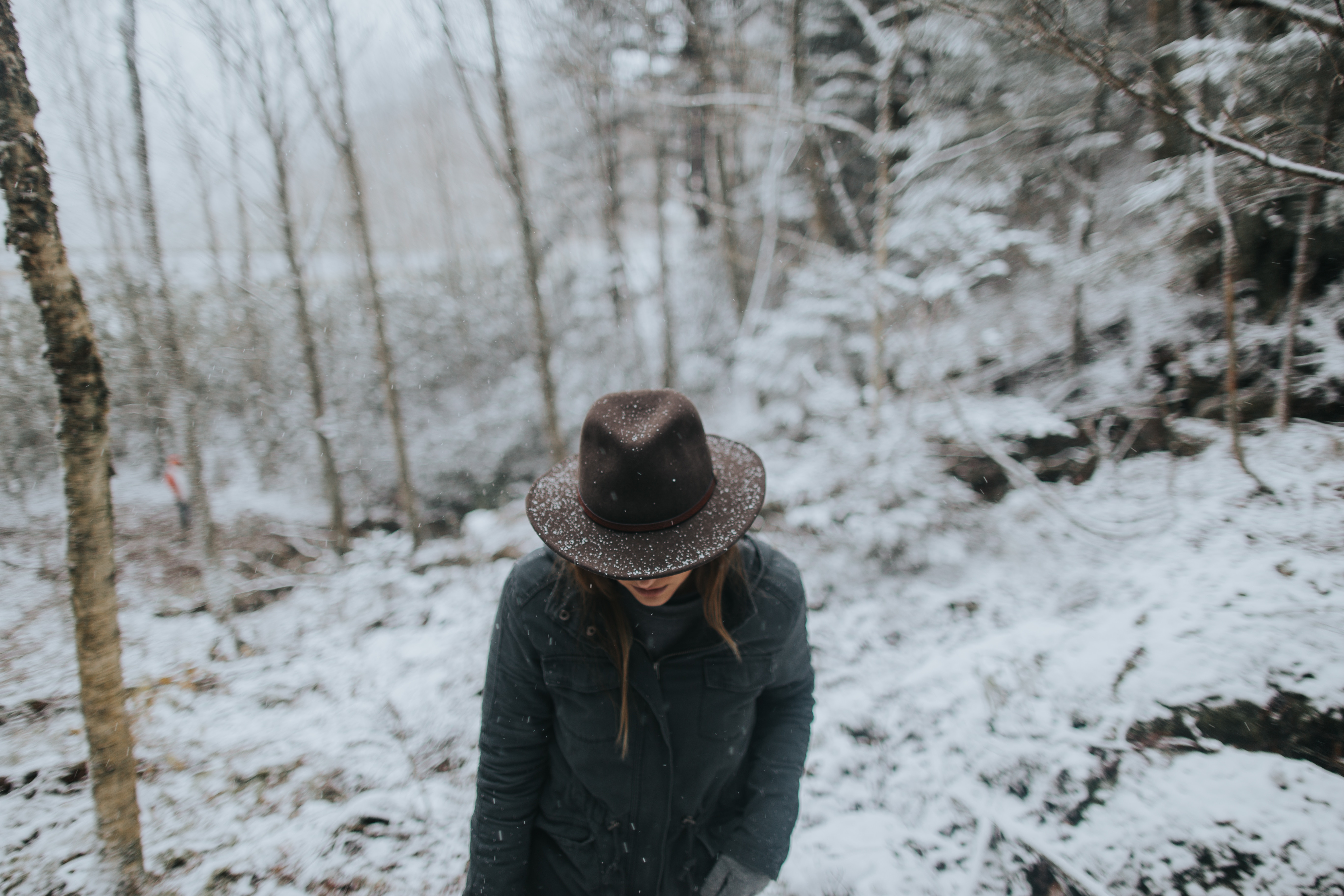 Woman in hat hiking in snowy woodland HD Wallpaper