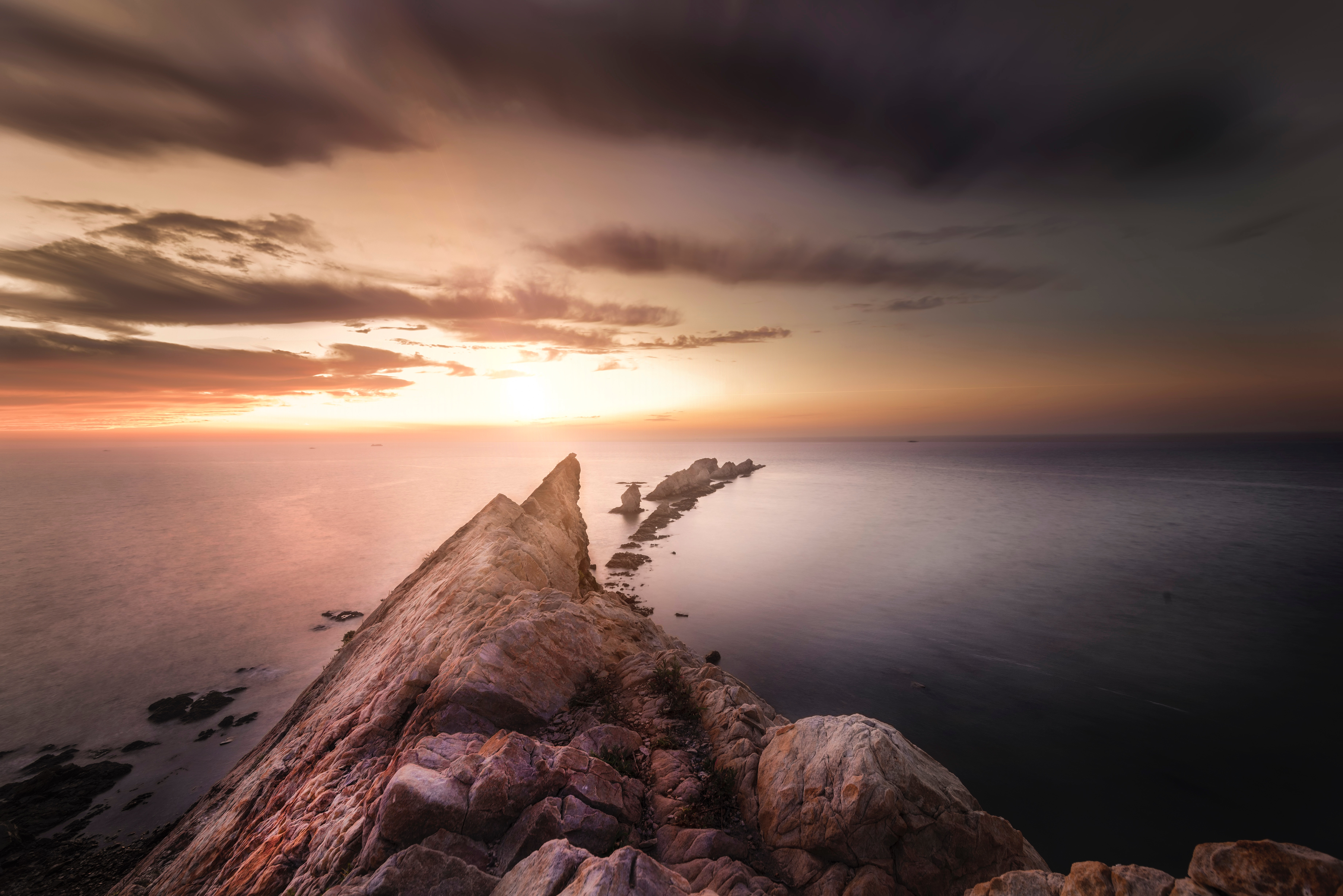 Rocky coastline at sunset with long exposure water HD Wallpaper
