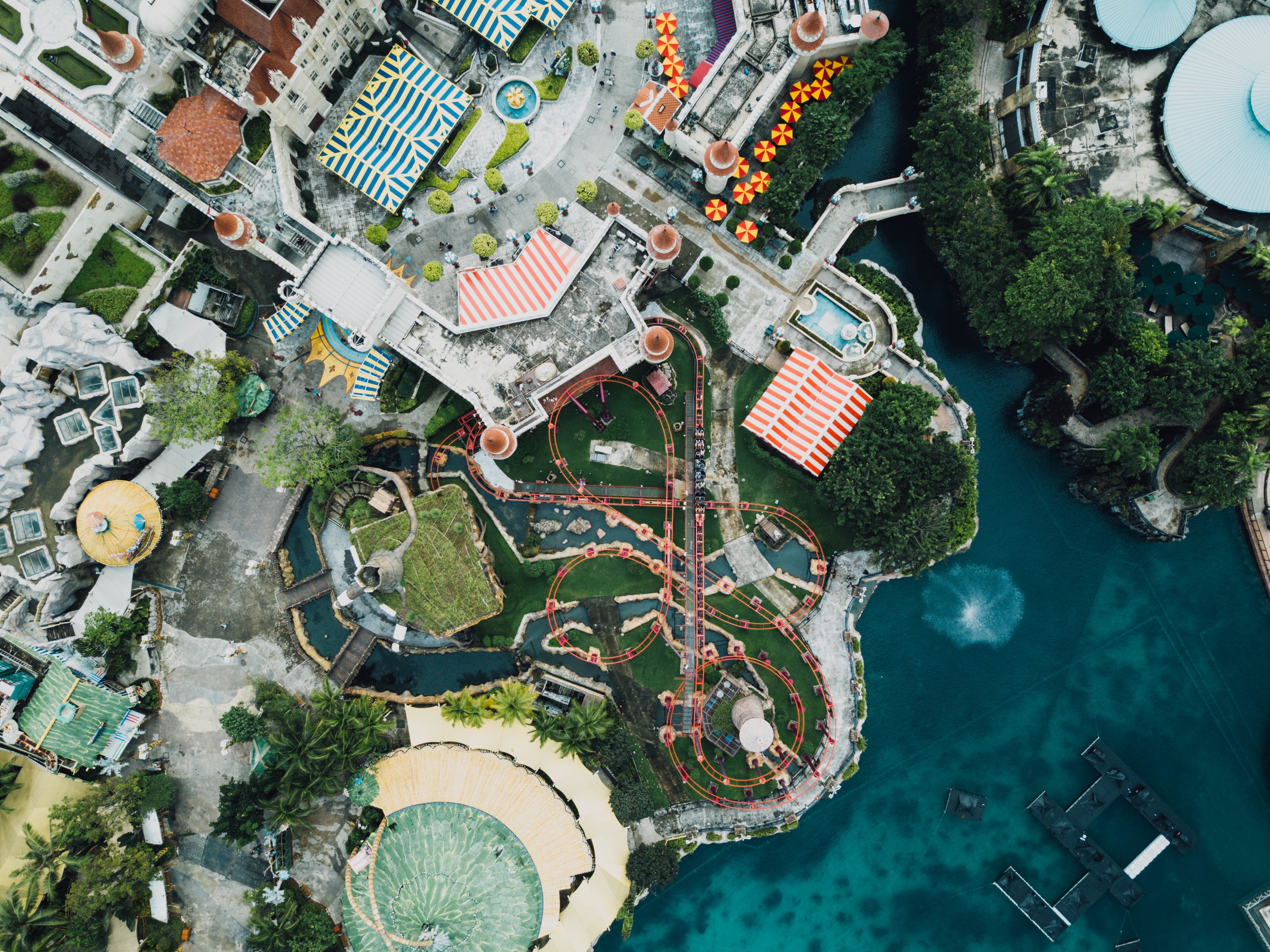 Aerial view of a theme park with a roller coaster and water features HD Wallpaper