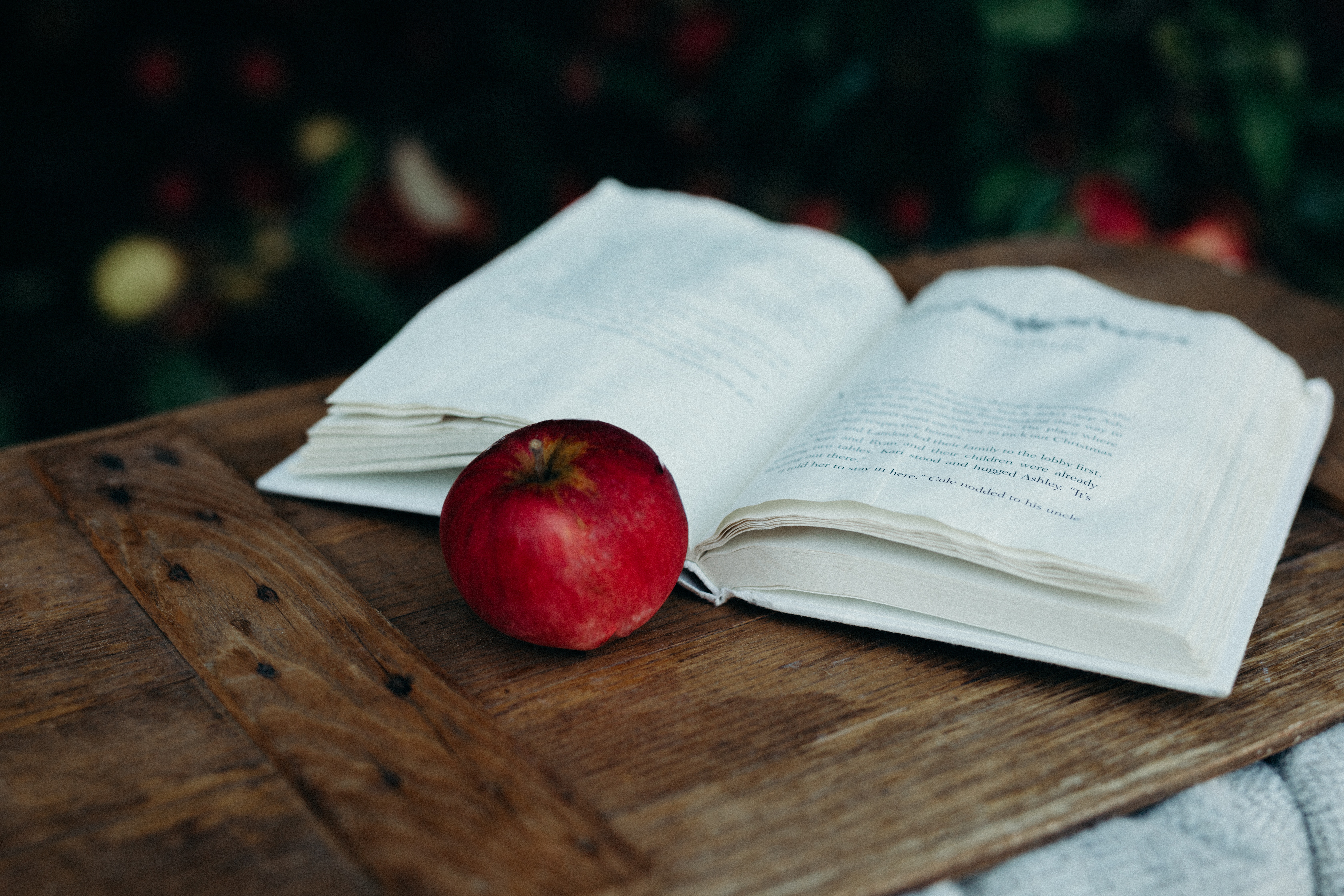 Open book and red apple on a wooden table HD Wallpaper