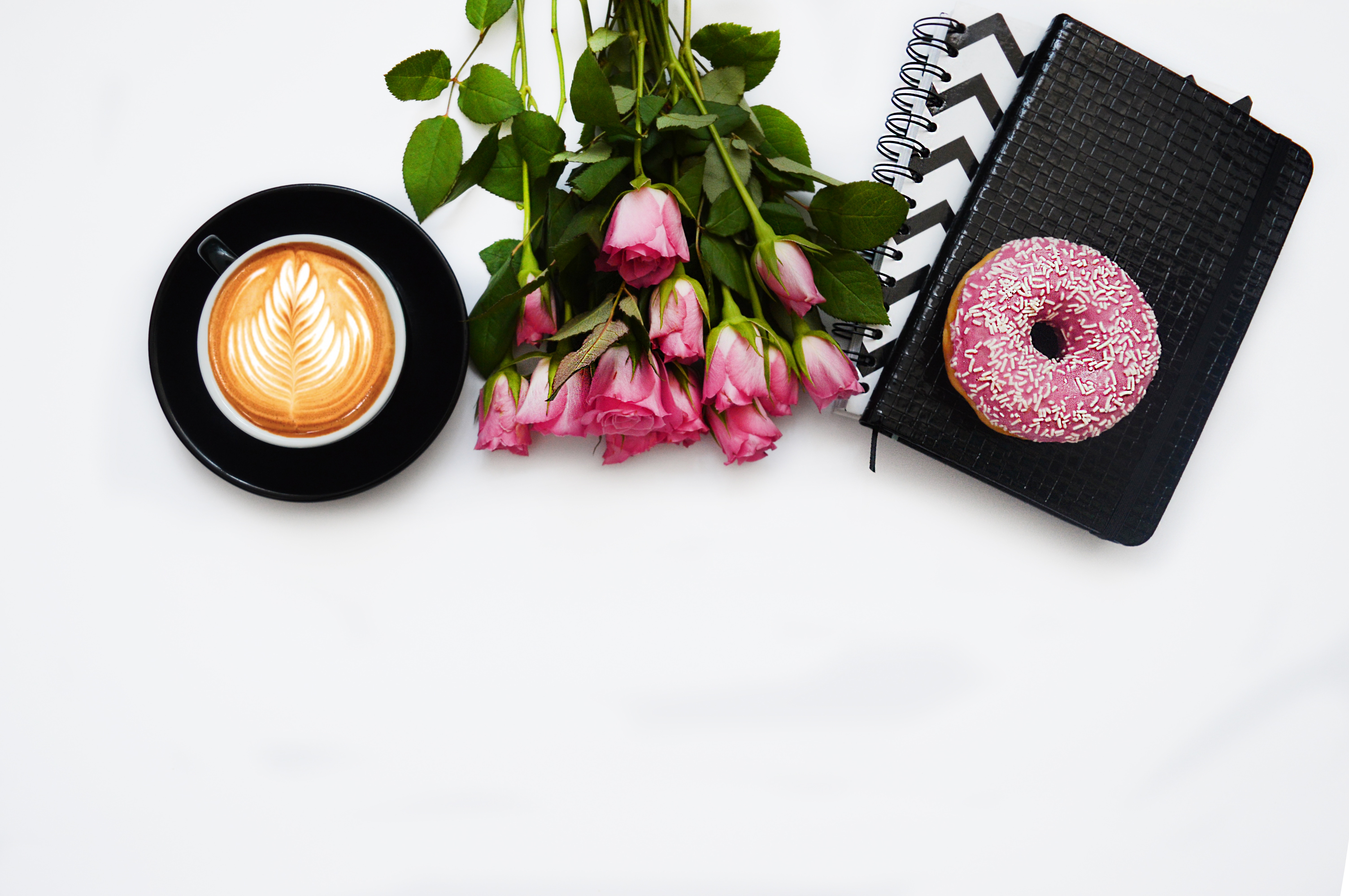 Flatlay of coffee, pink roses, donut, and notebooks HD Wallpaper