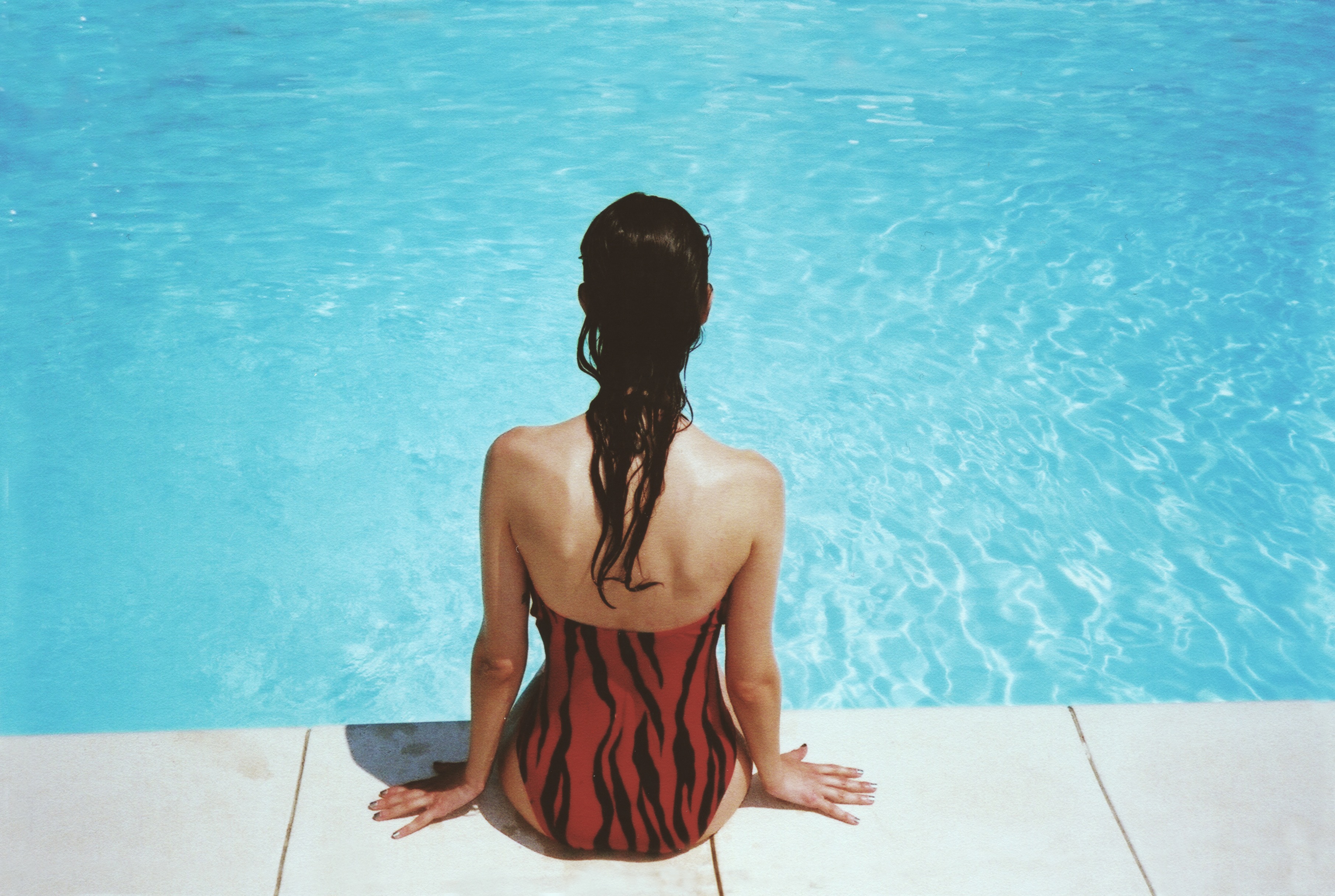 Woman Sitting Poolside in Red Striped Swimsuit HD Wallpaper