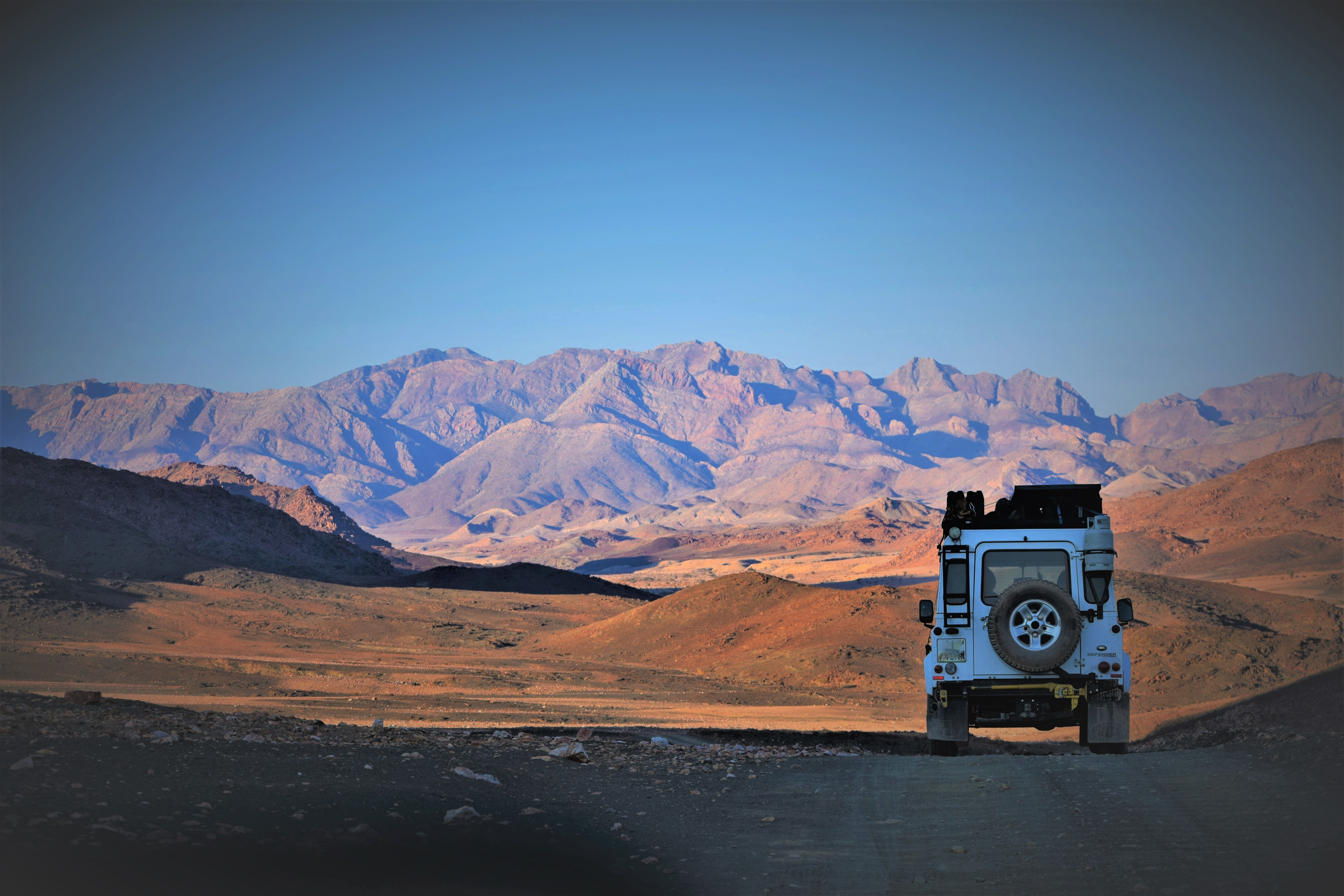 White 4x4 vehicle parked in a desert landscape with mountains HD Wallpaper