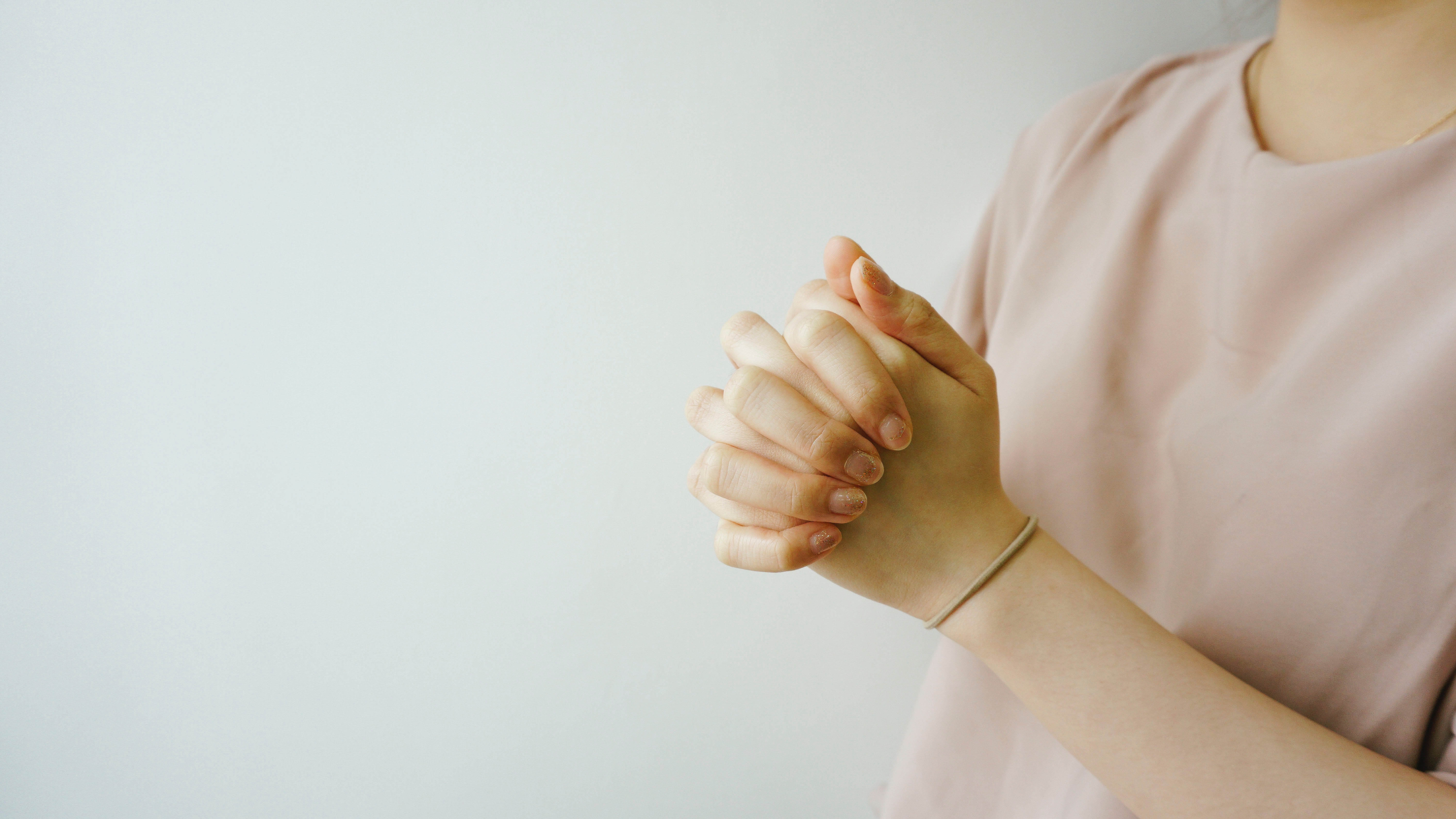 Person praying with hands clasped HD Wallpaper
