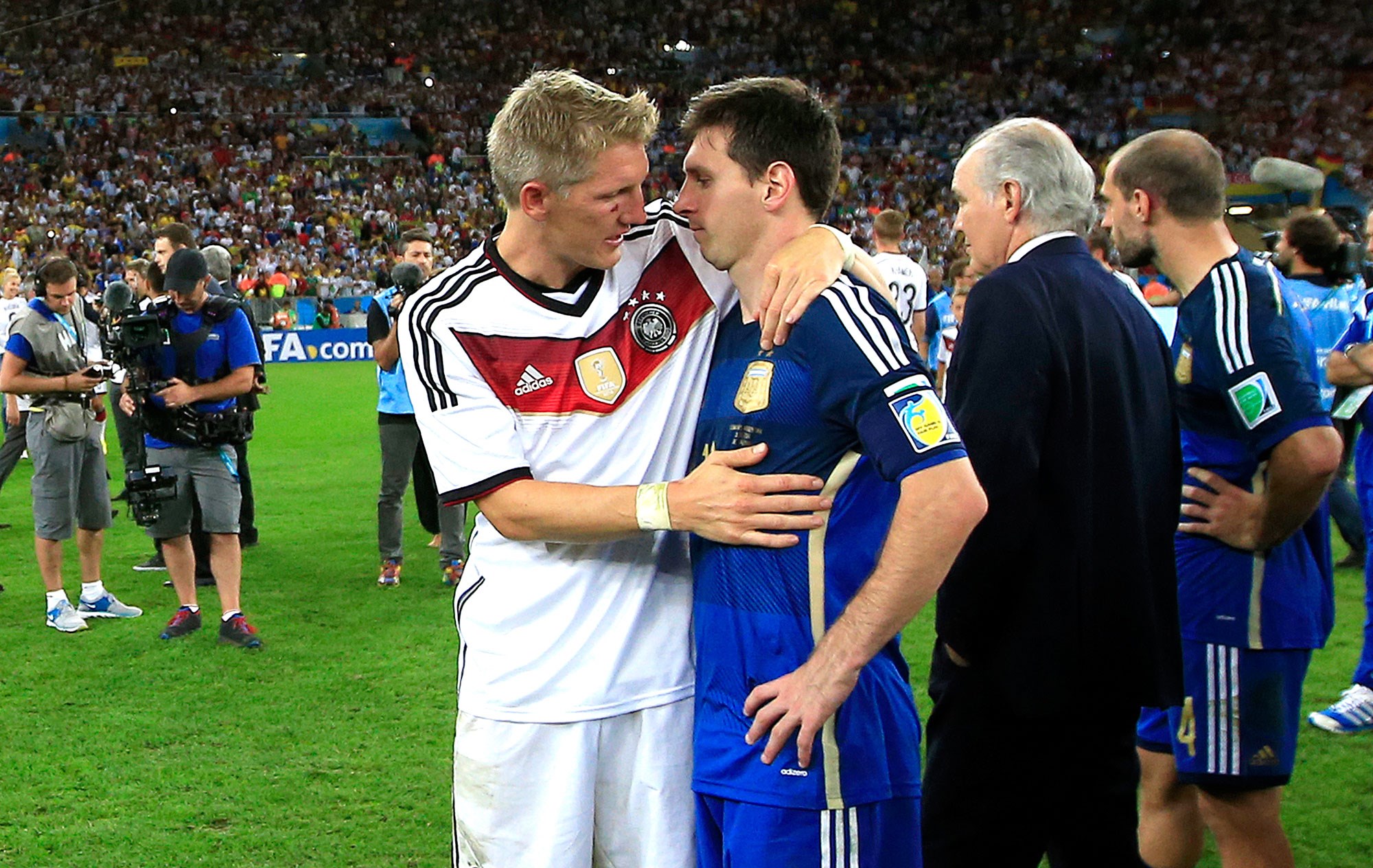 Lionel Messi and Bastian Schweinsteiger embrace on a soccer field HD Wallpaper
