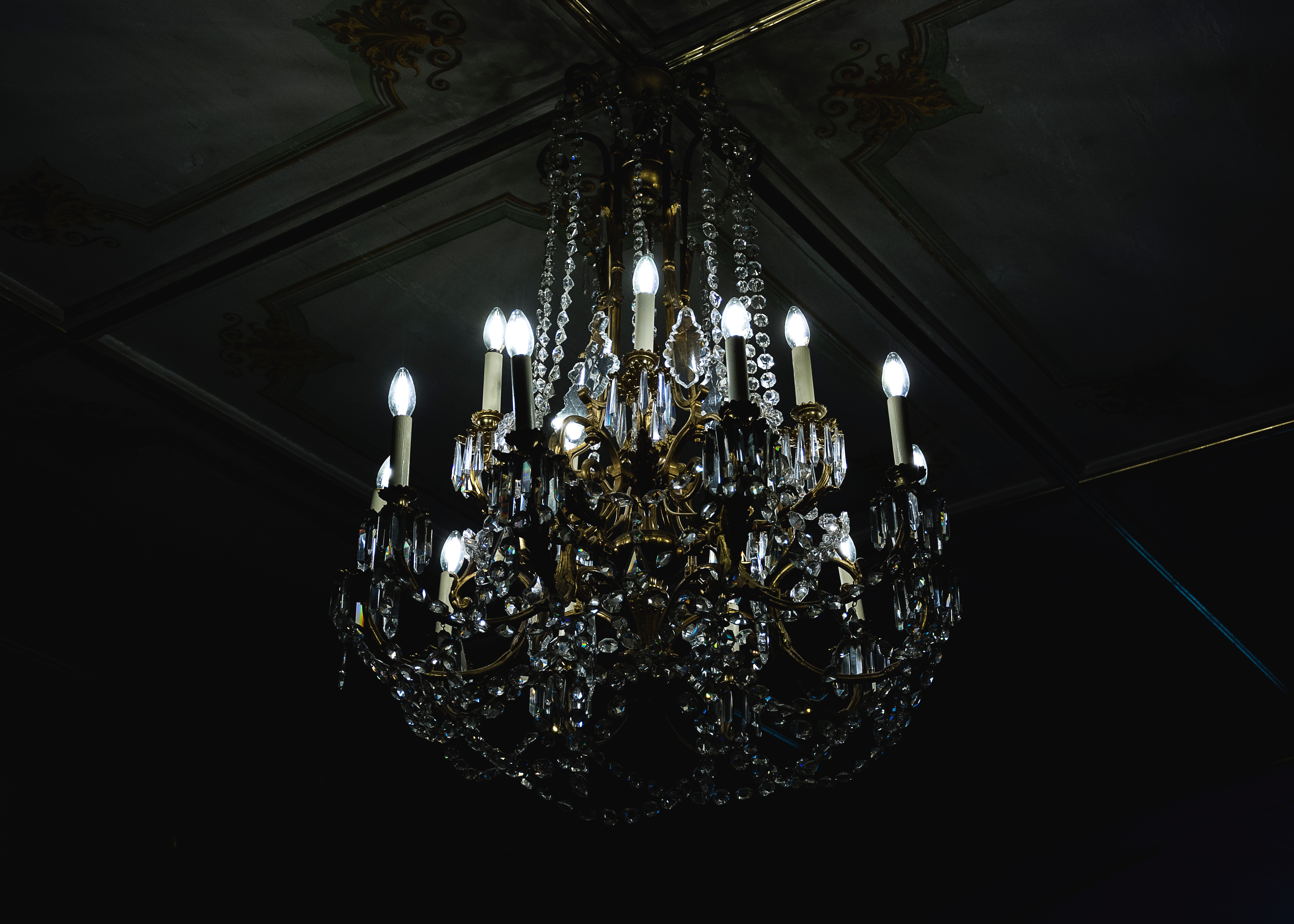 Vintage crystal chandelier hanging from a decorated ceiling HD Wallpaper