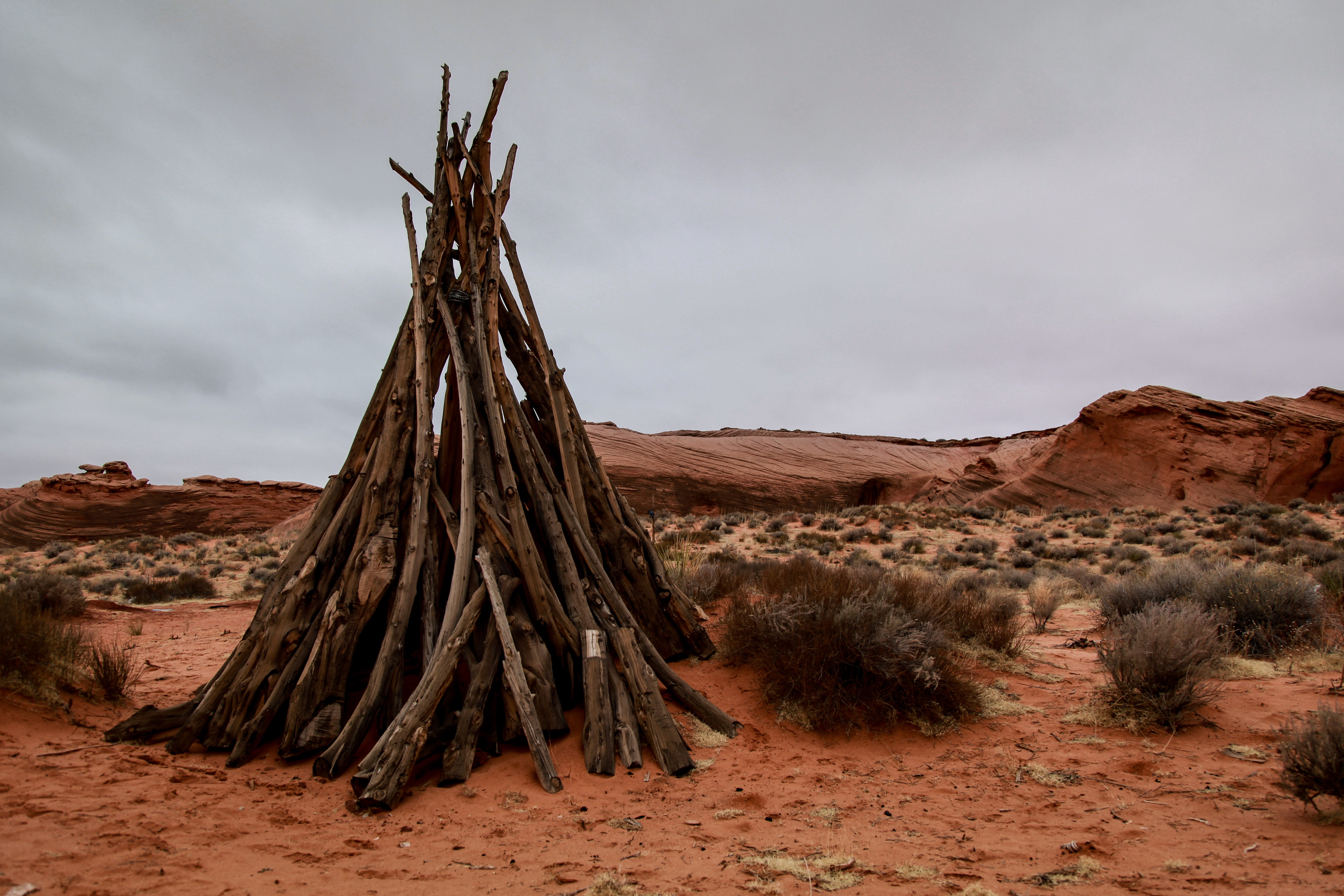 Teepee made of sticks in a desert landscape HD Wallpaper