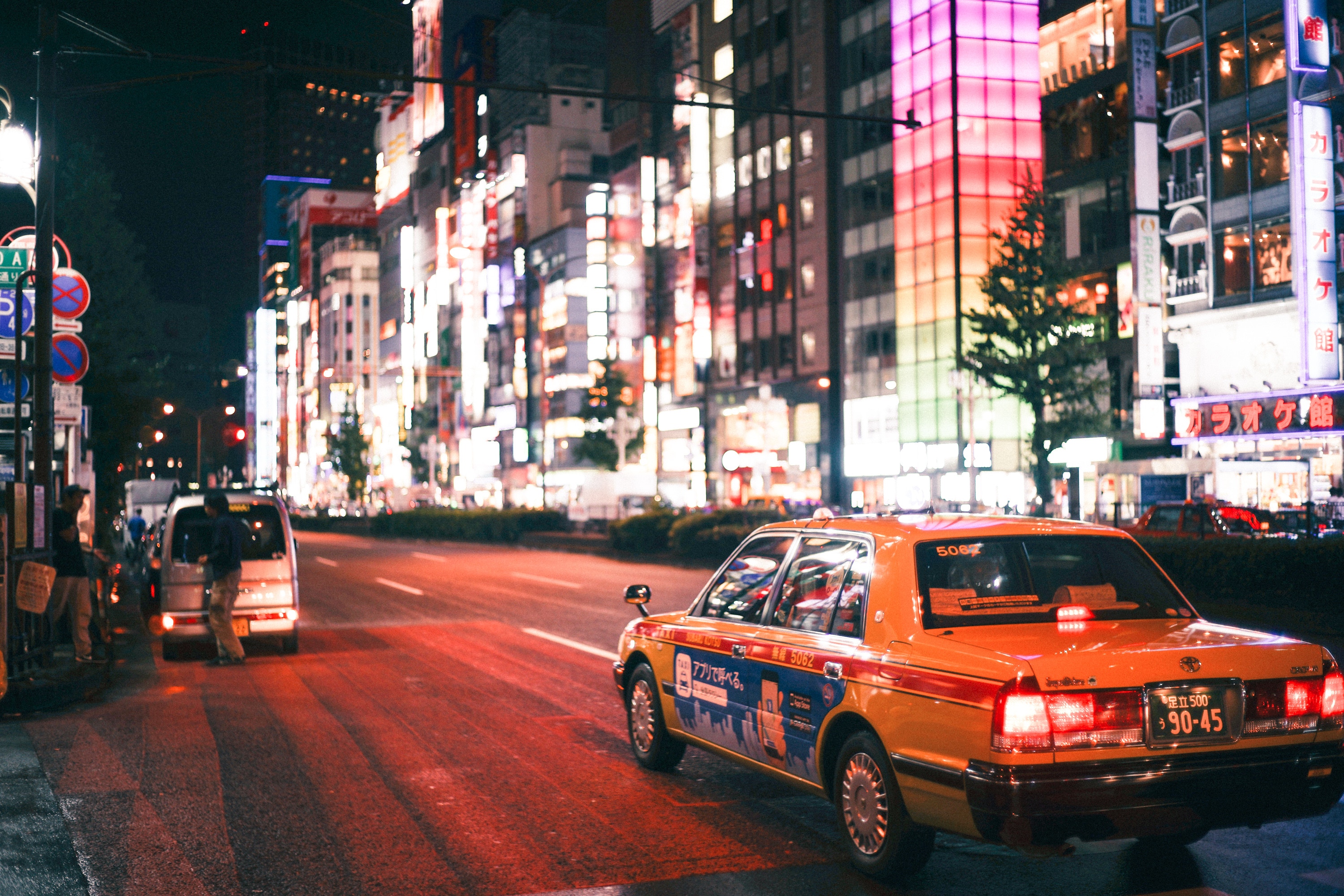 Tokyo street at night with a taxi and neon lights HD Wallpaper